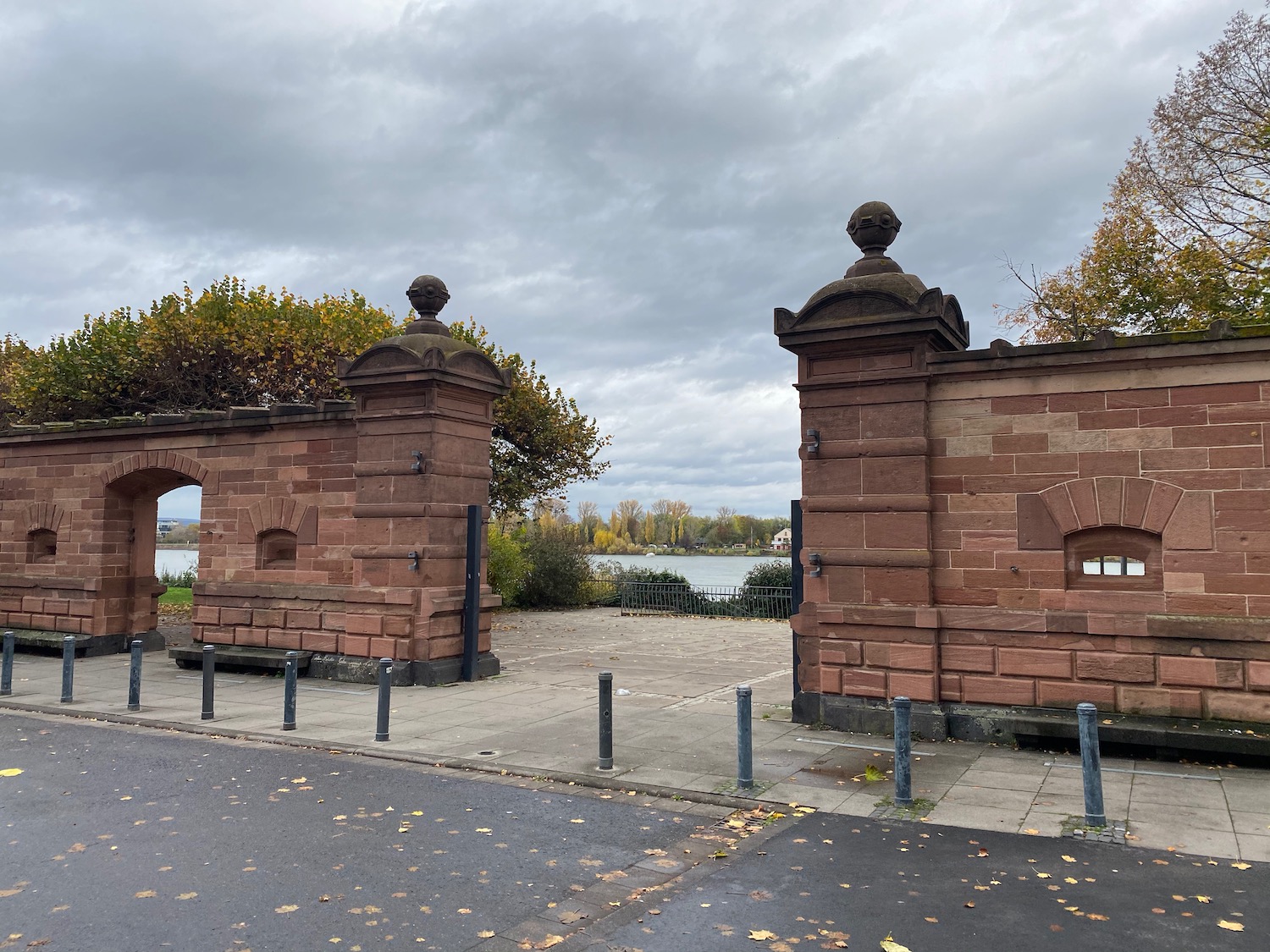 a brick gate with trees and a body of water in the background