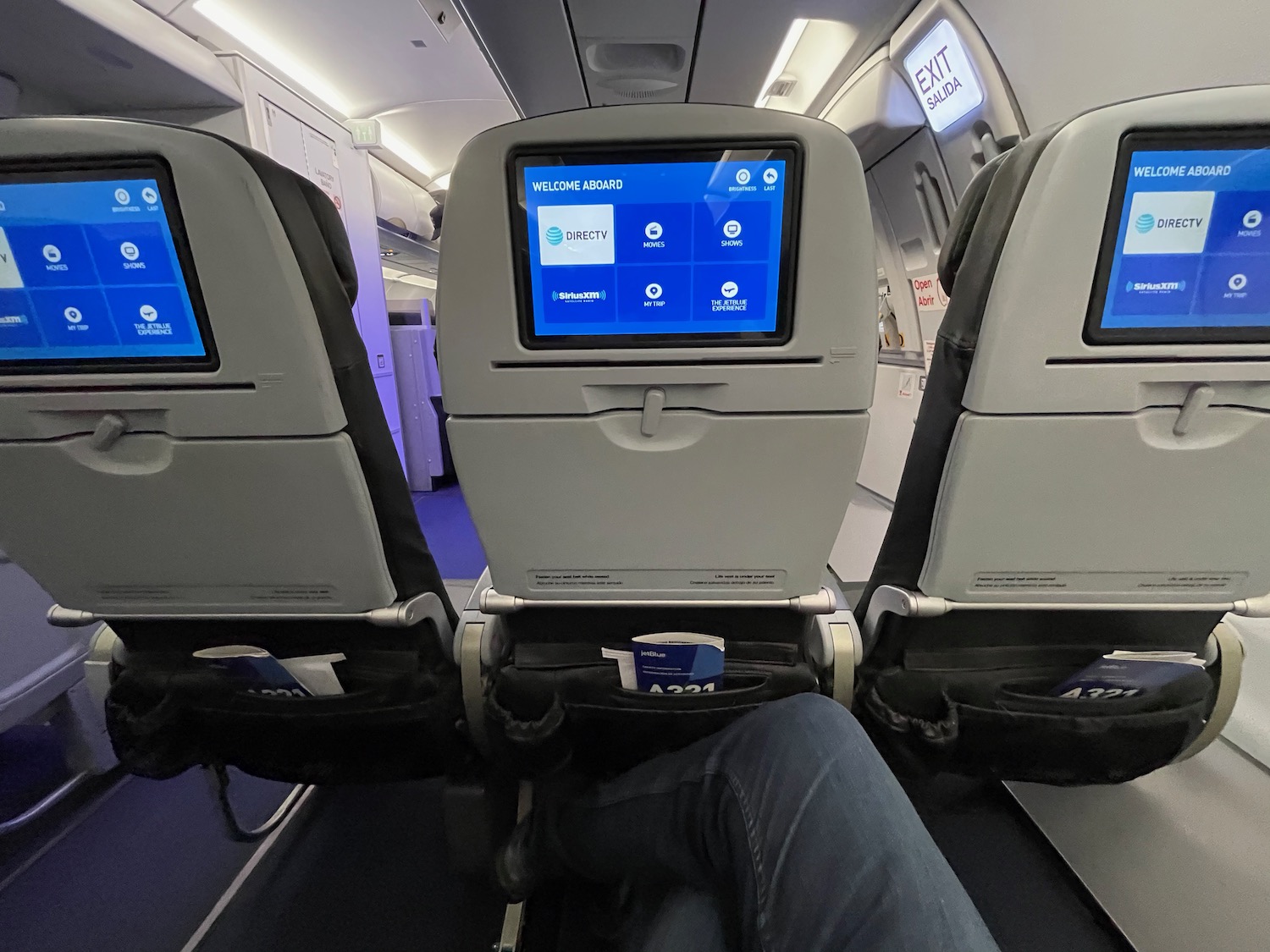 a person's legs in an airplane with a screen on the back