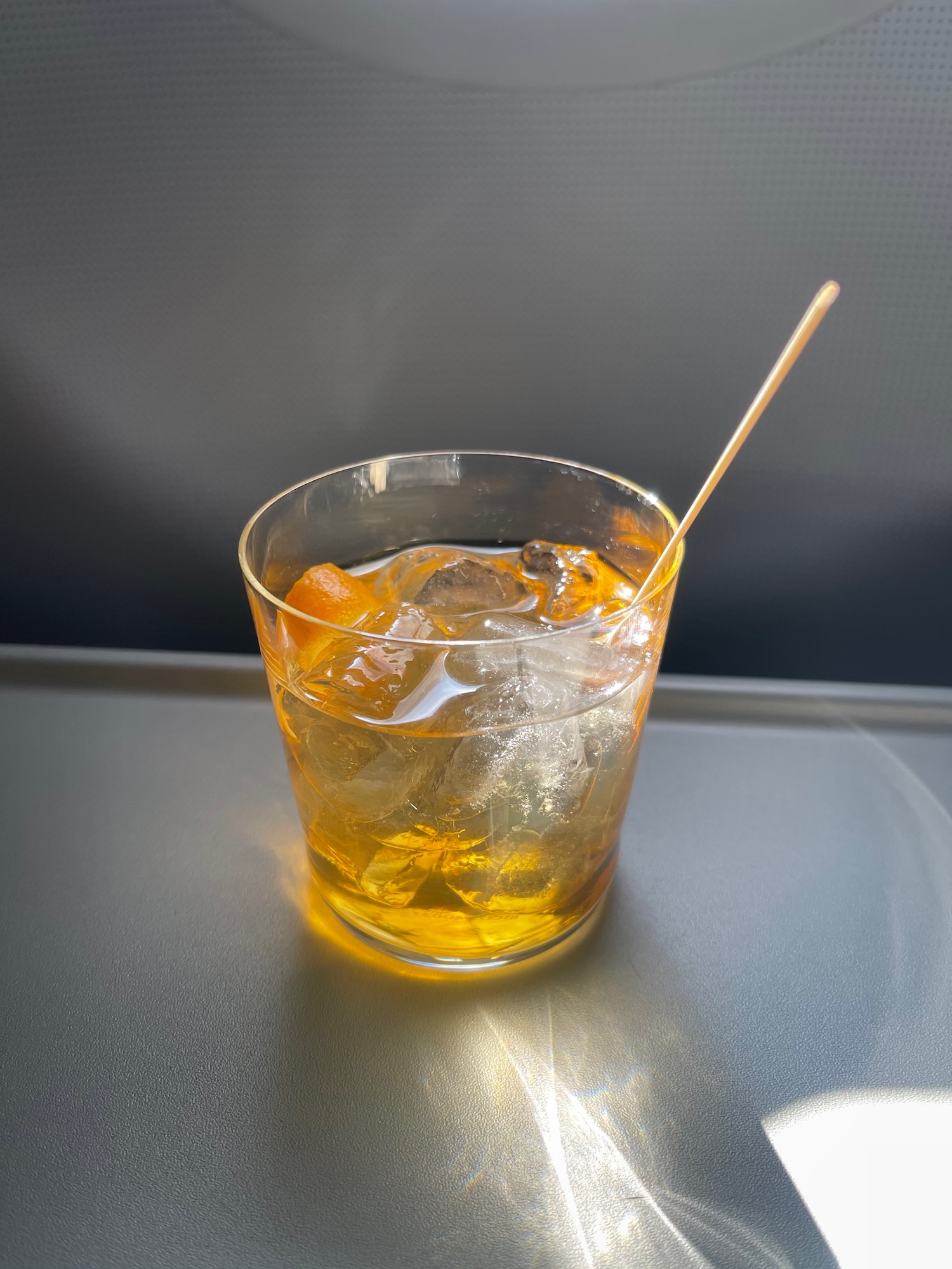 a glass of liquid with ice and a toothpick