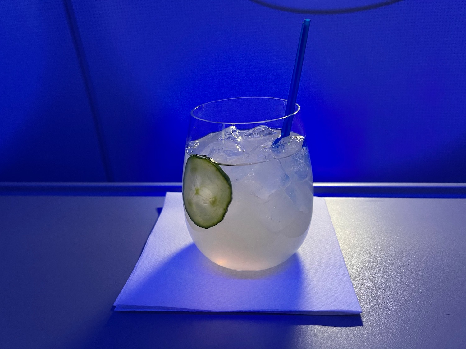 a glass with ice and cucumber on a napkin