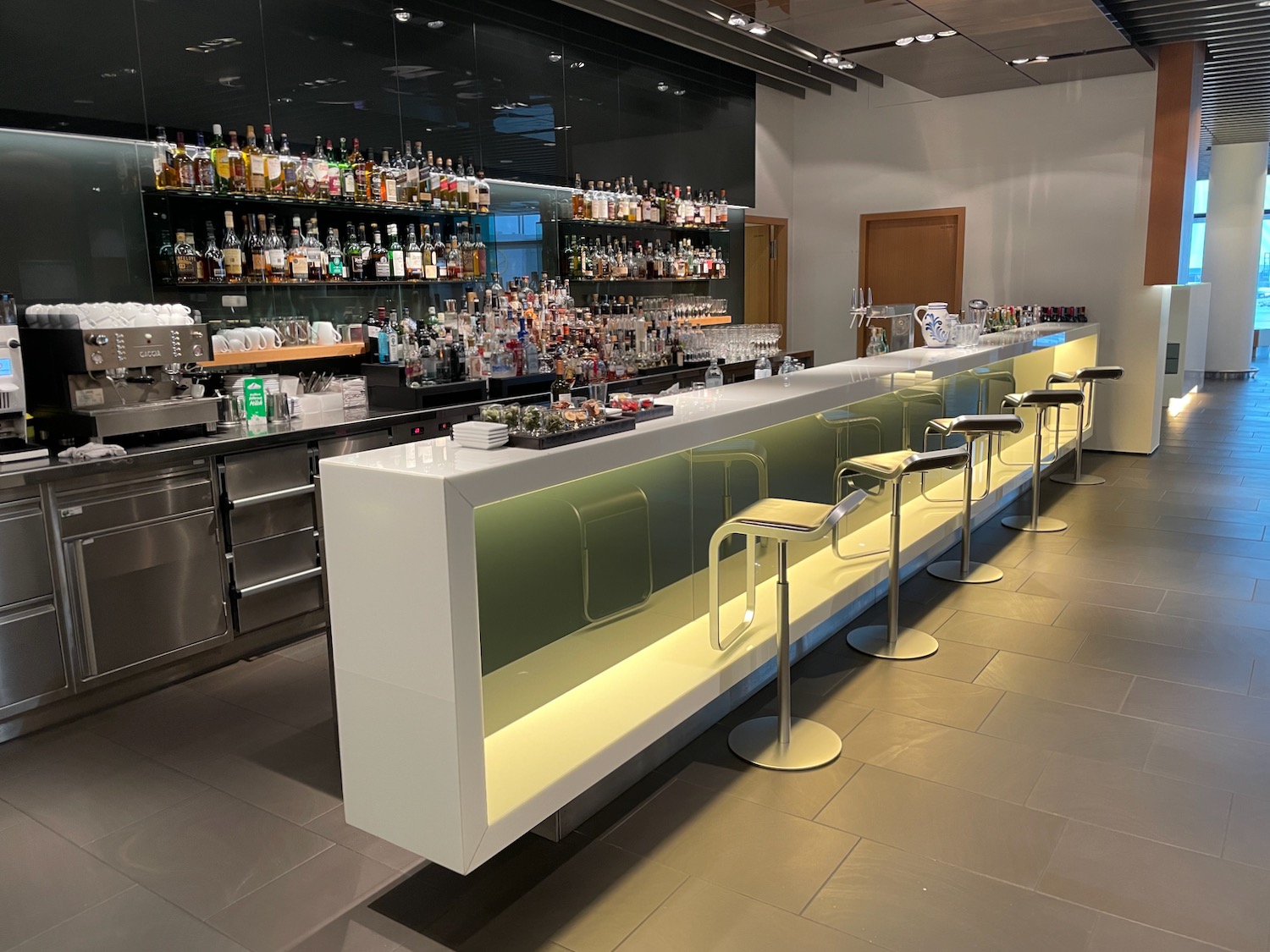 a bar with a row of stools and bottles on the wall