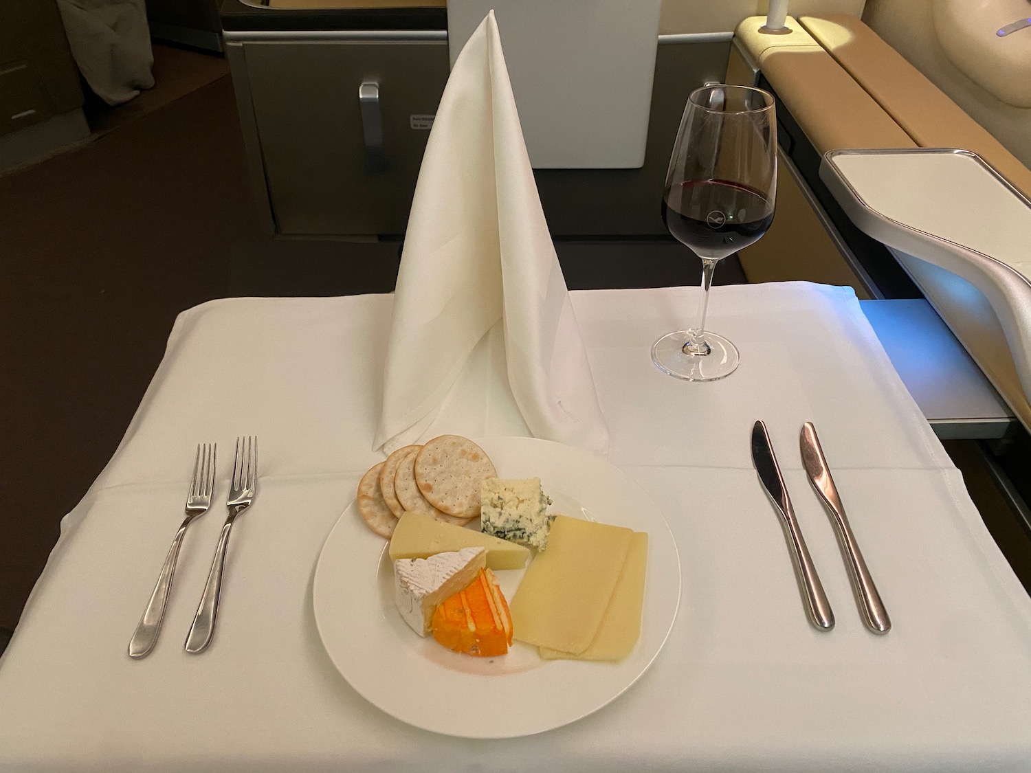 a plate of cheese and crackers on a table with a glass of wine