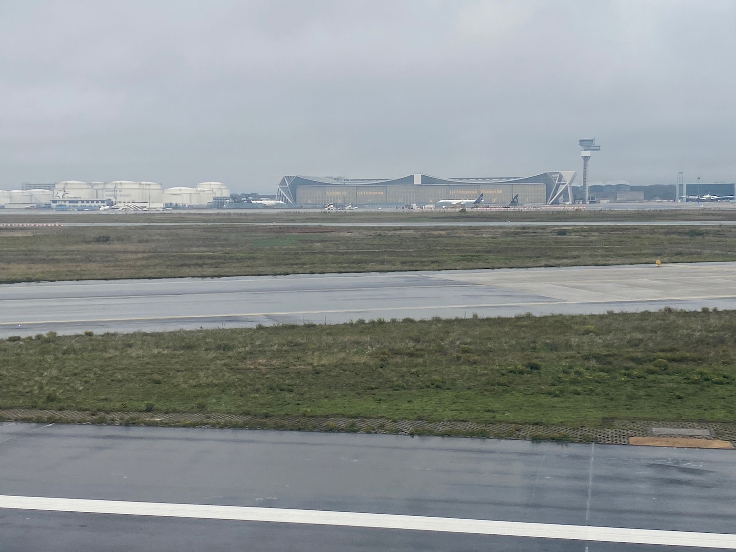 a runway with grass and buildings in the background