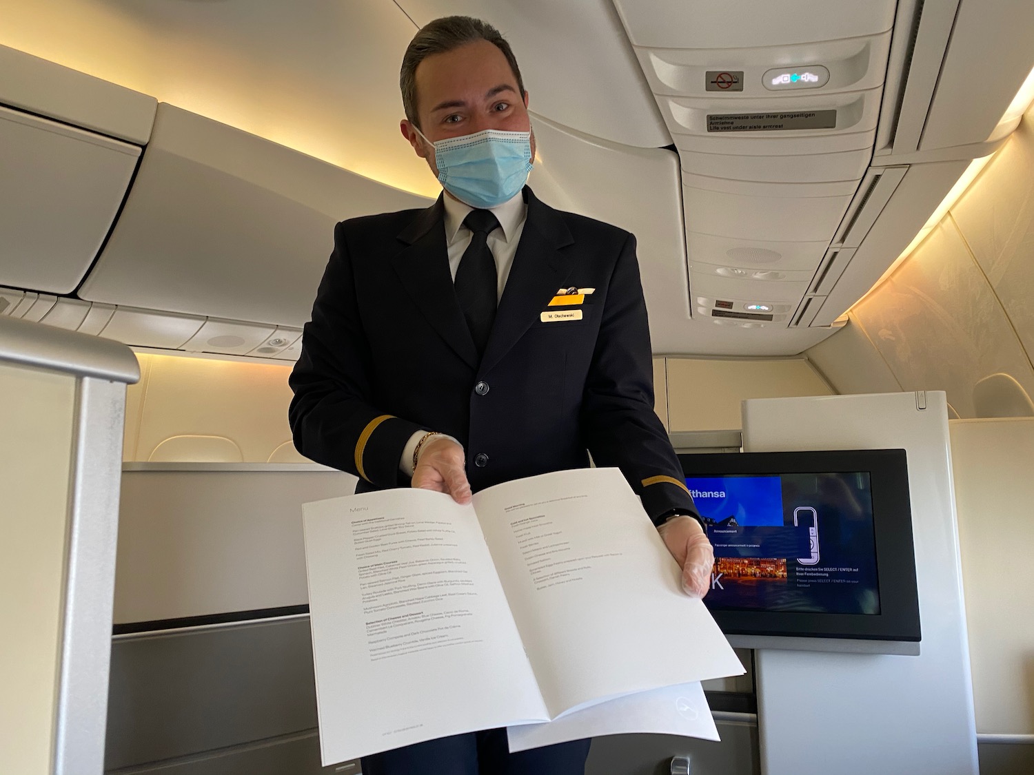 a man wearing a mask and holding a book in an airplane