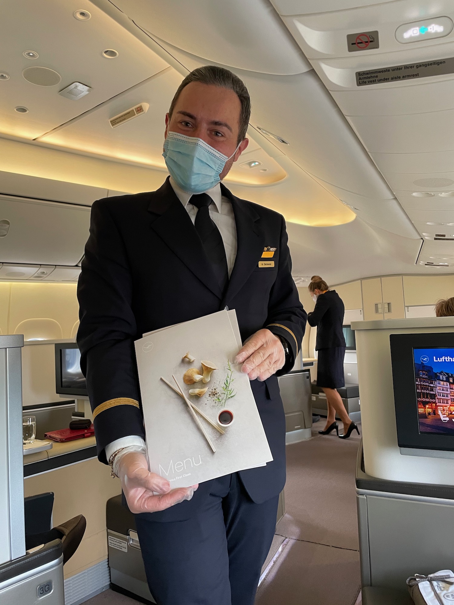 a man wearing a mask and holding a menu in an airplane