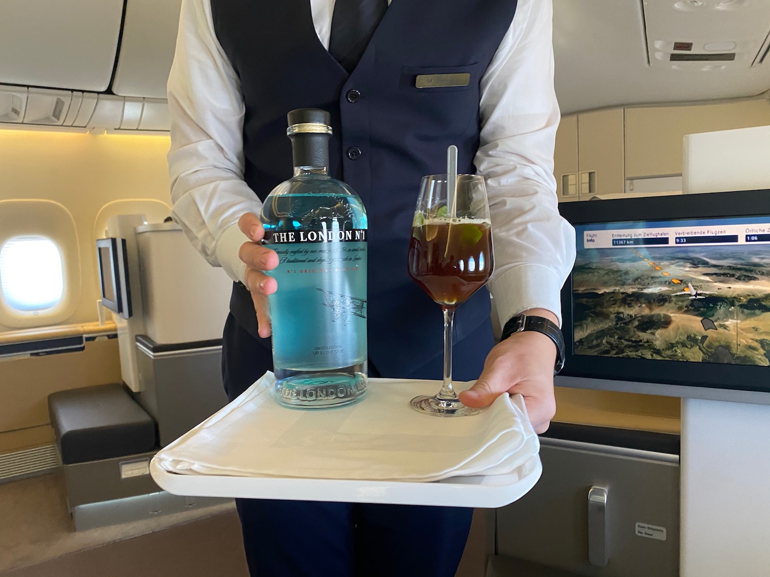 a person holding a tray with a bottle and a drink