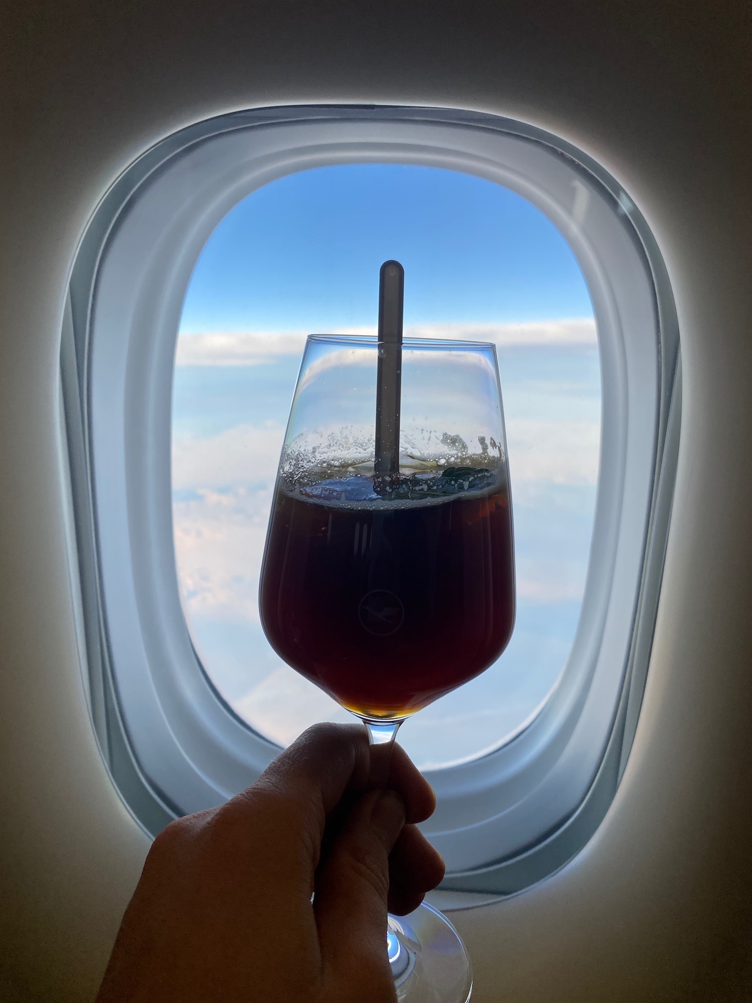 a hand holding a glass of brown liquid