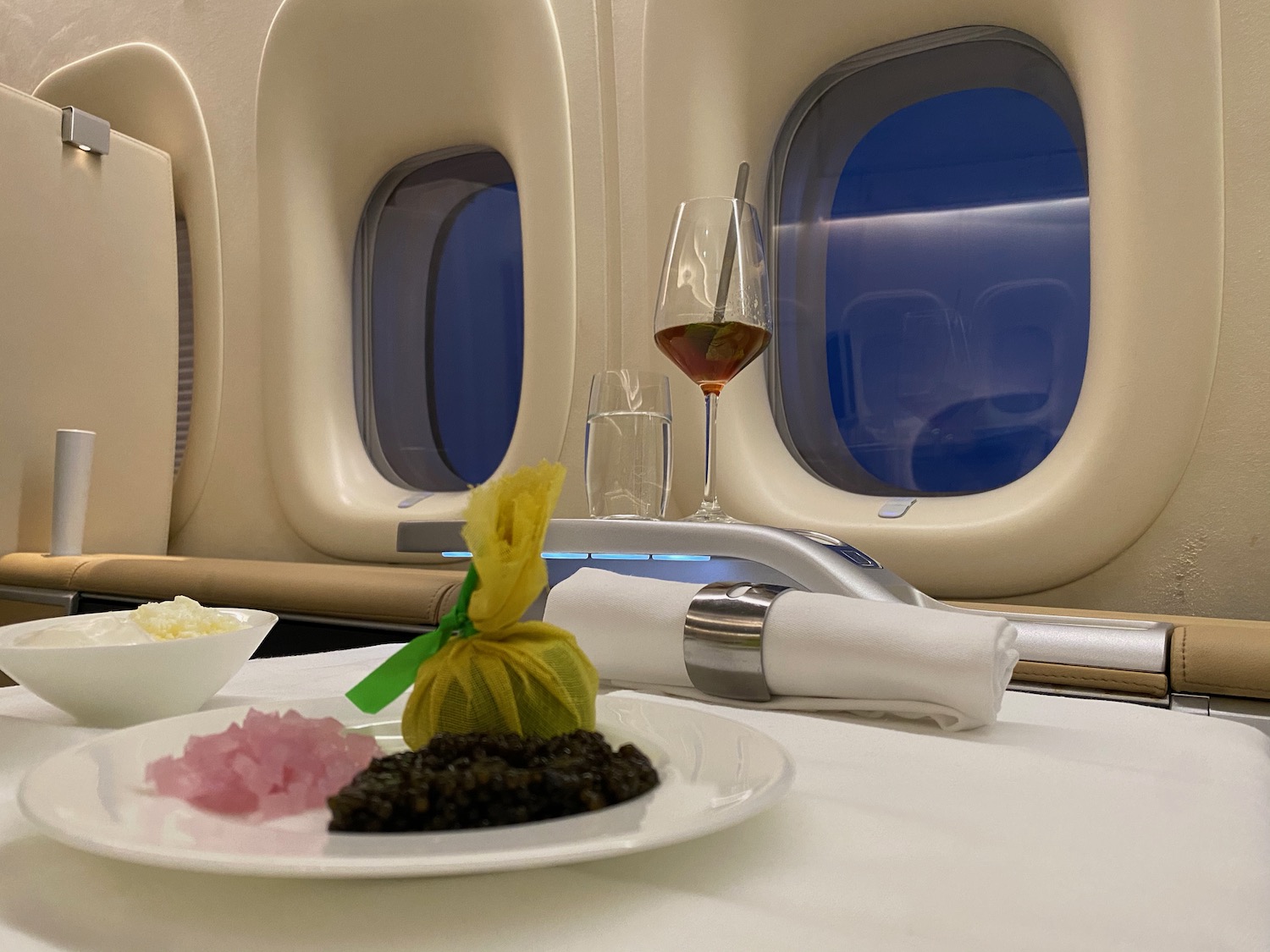 a plate of food on a table with a glass of wine and windows