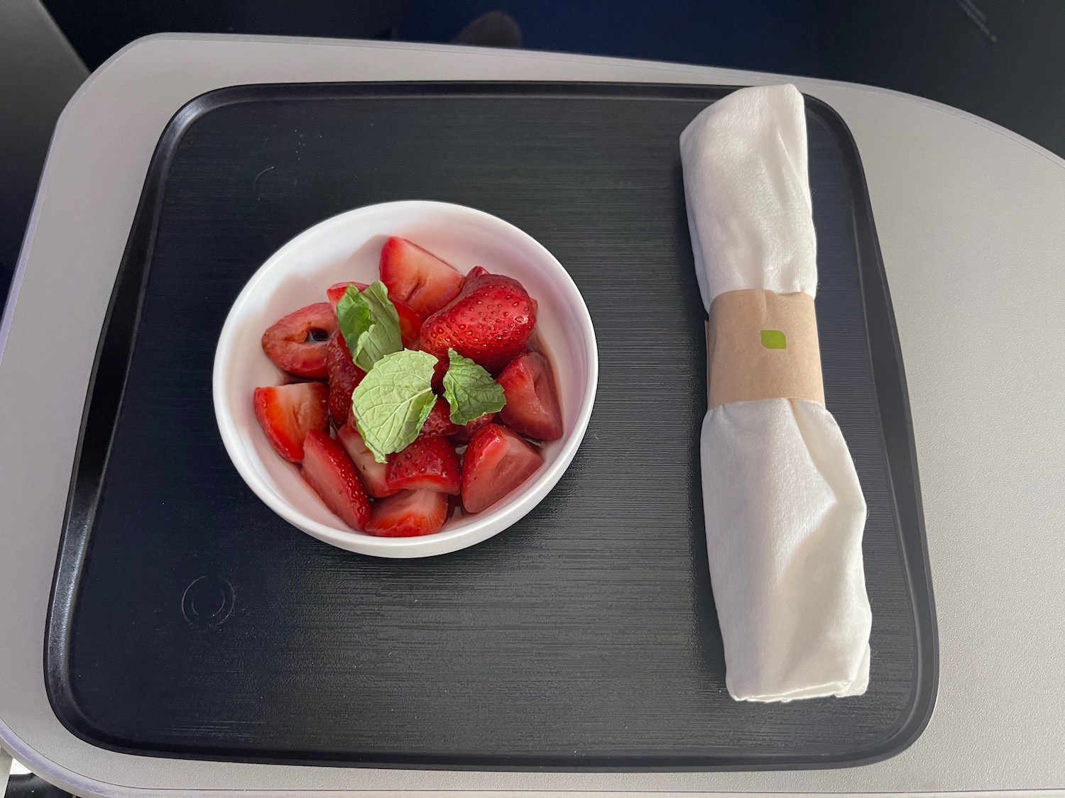 a bowl of strawberries and a napkin on a tray