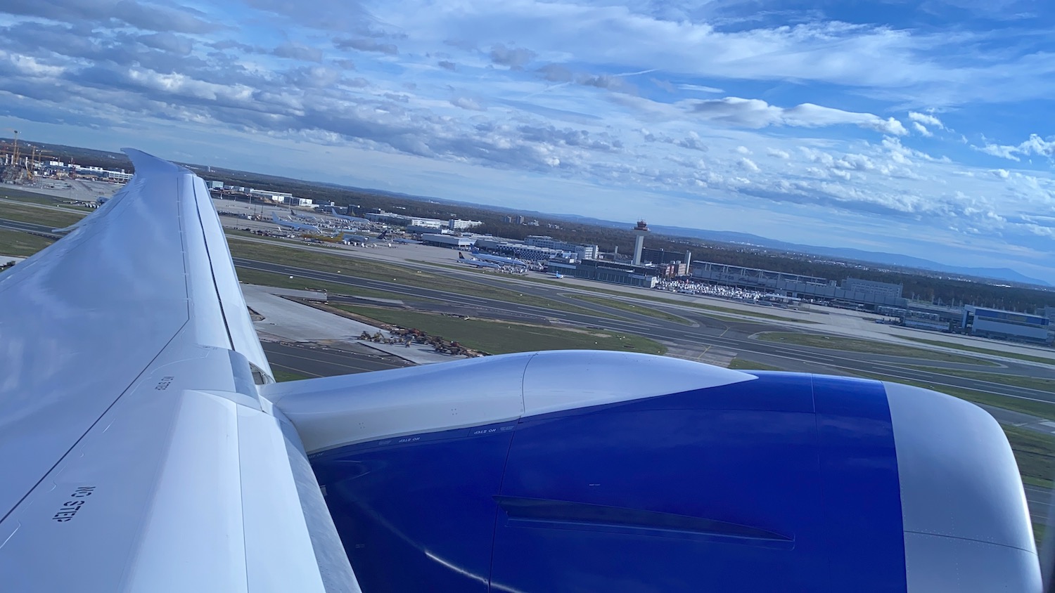 an airplane wing and runway with buildings in the background