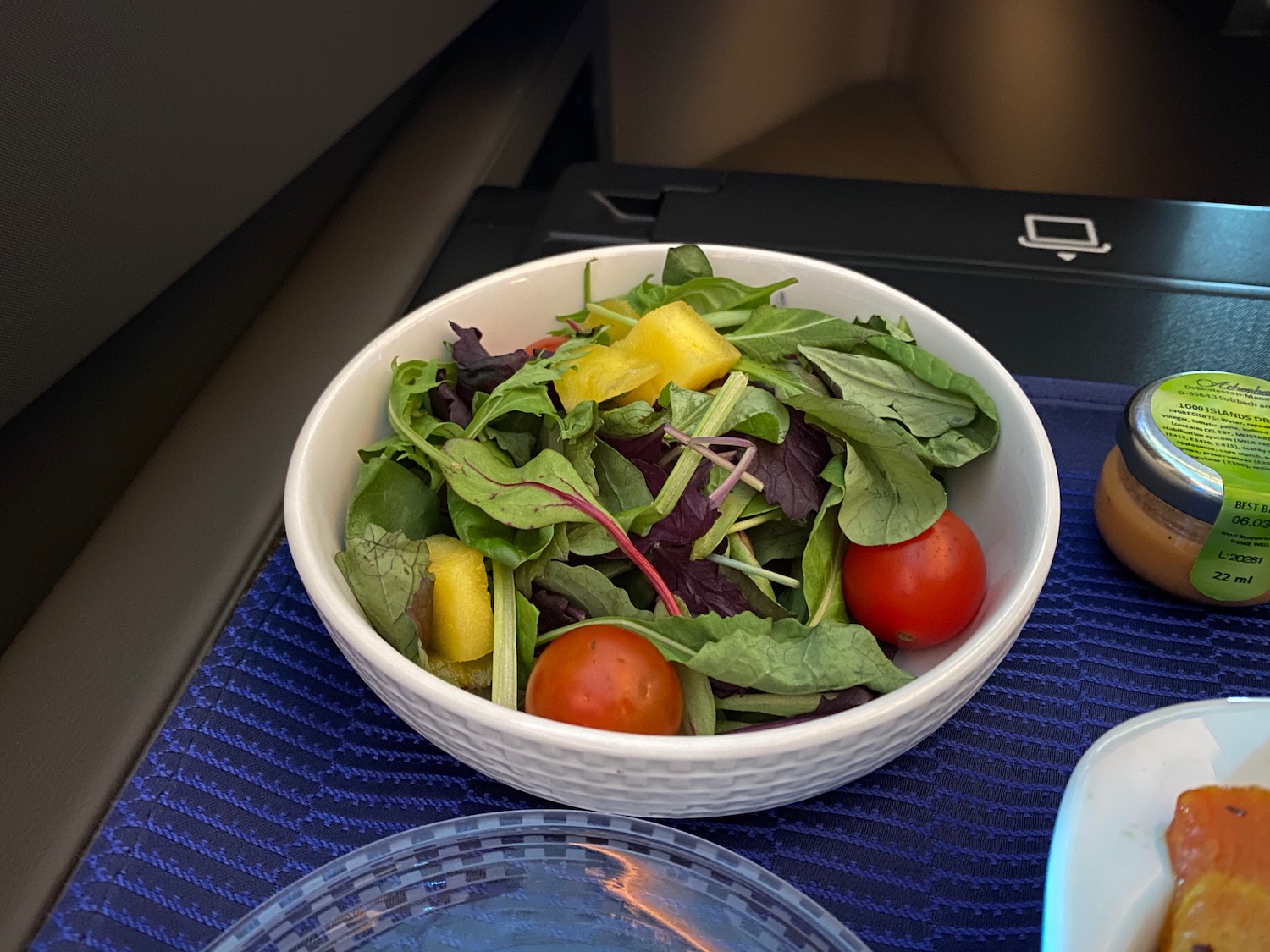 a bowl of salad on a blue place mat