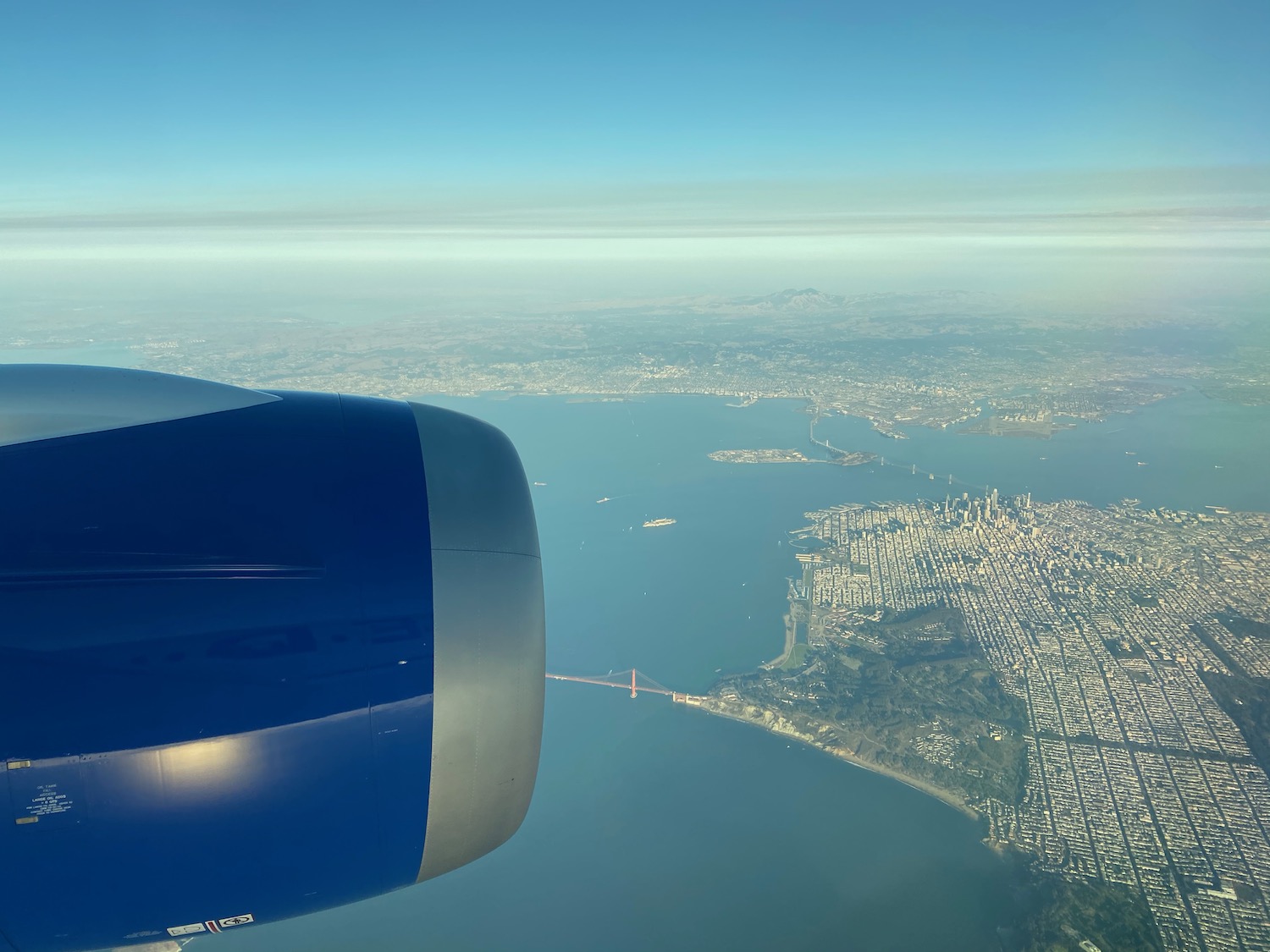 an airplane wing with a body of water and a city