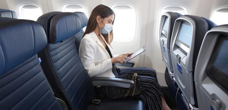 a woman wearing a mask on her face sitting in an airplane