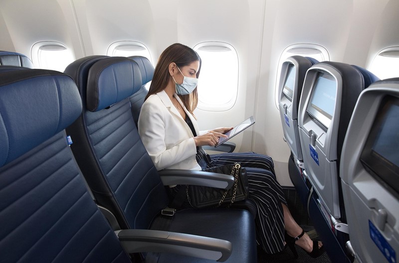 a woman wearing a mask on her face sitting in an airplane