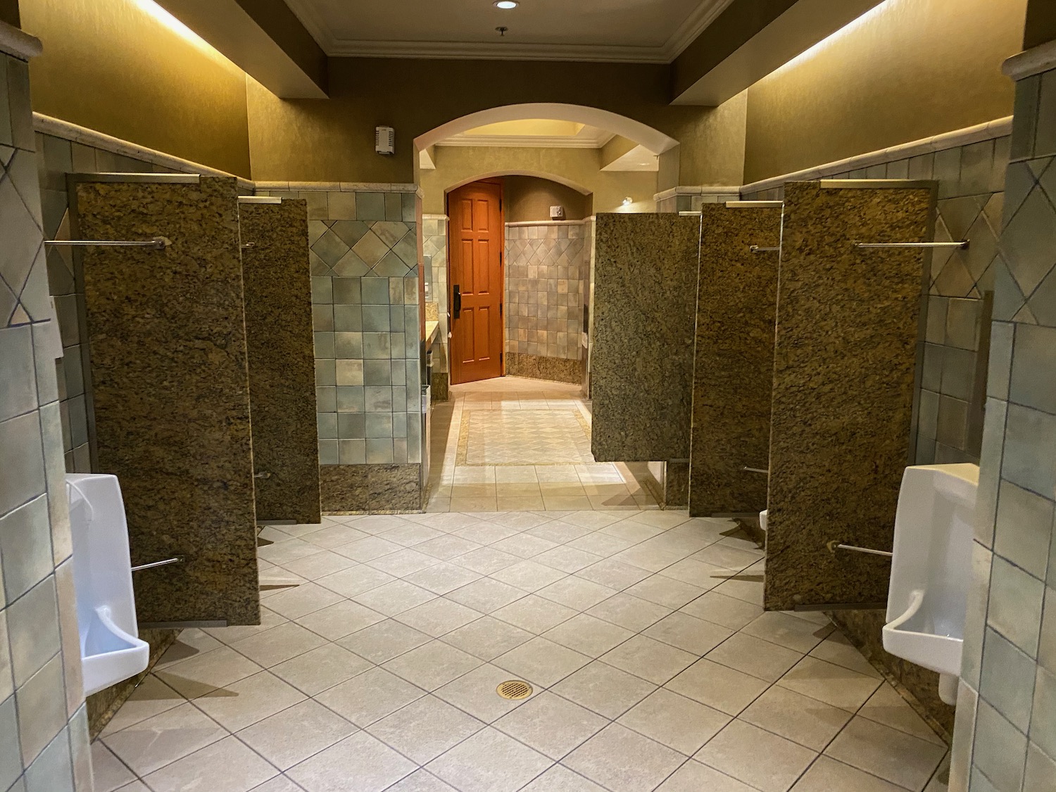 a bathroom with urinals and tiled floor