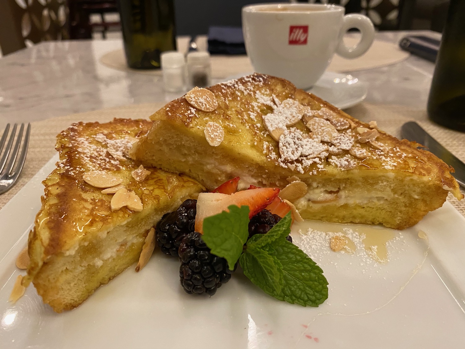 a plate of french toast with fruit and a cup of coffee