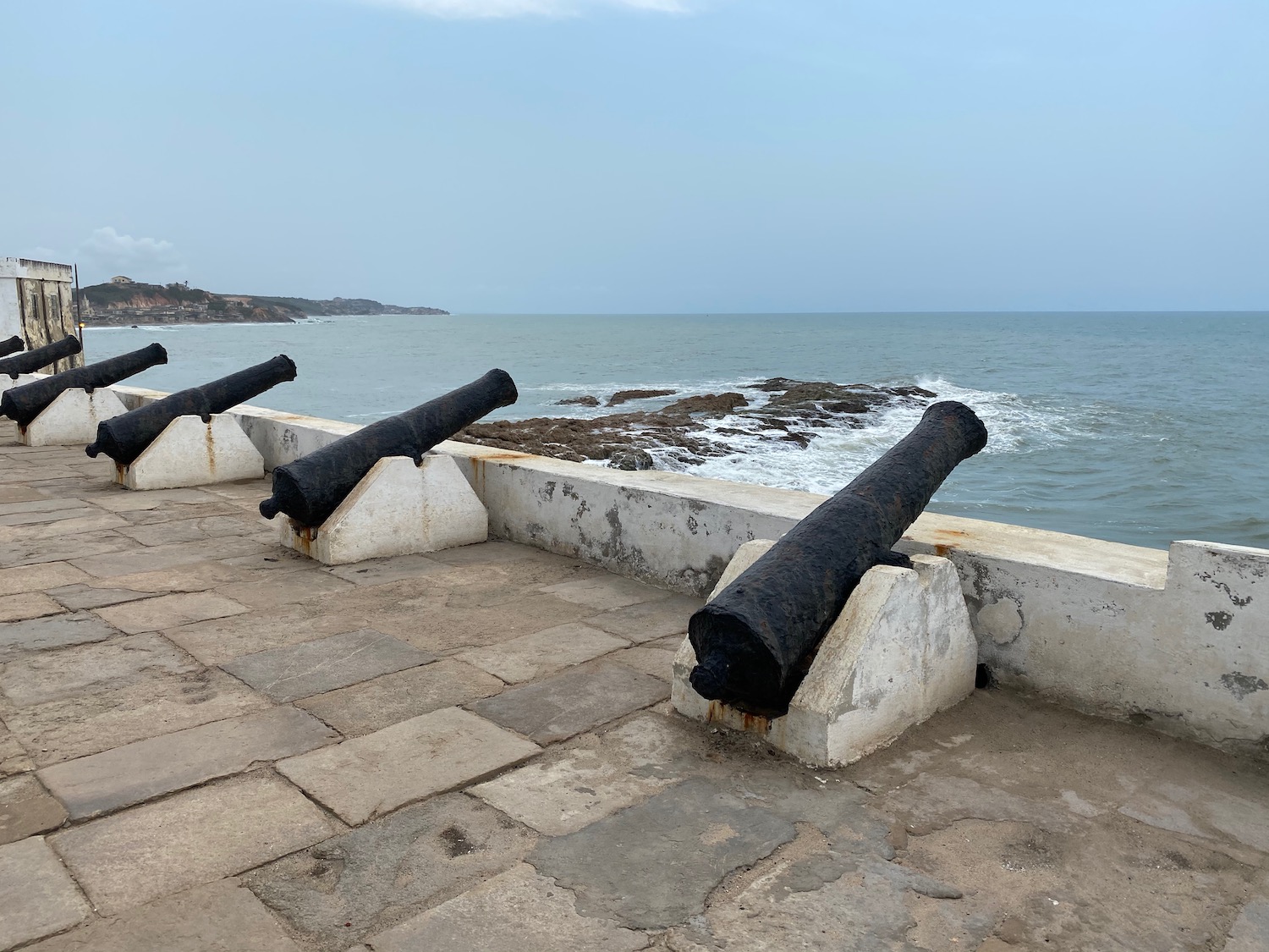 cannons on a stone wall next to a body of water