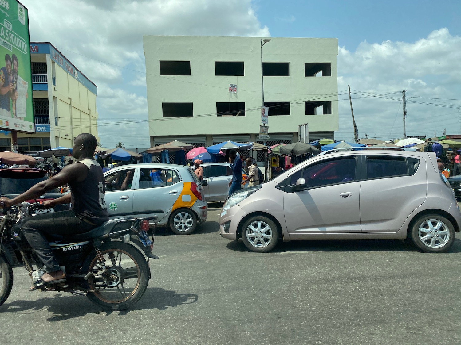 a man riding a motorcycle in a street with cars and people