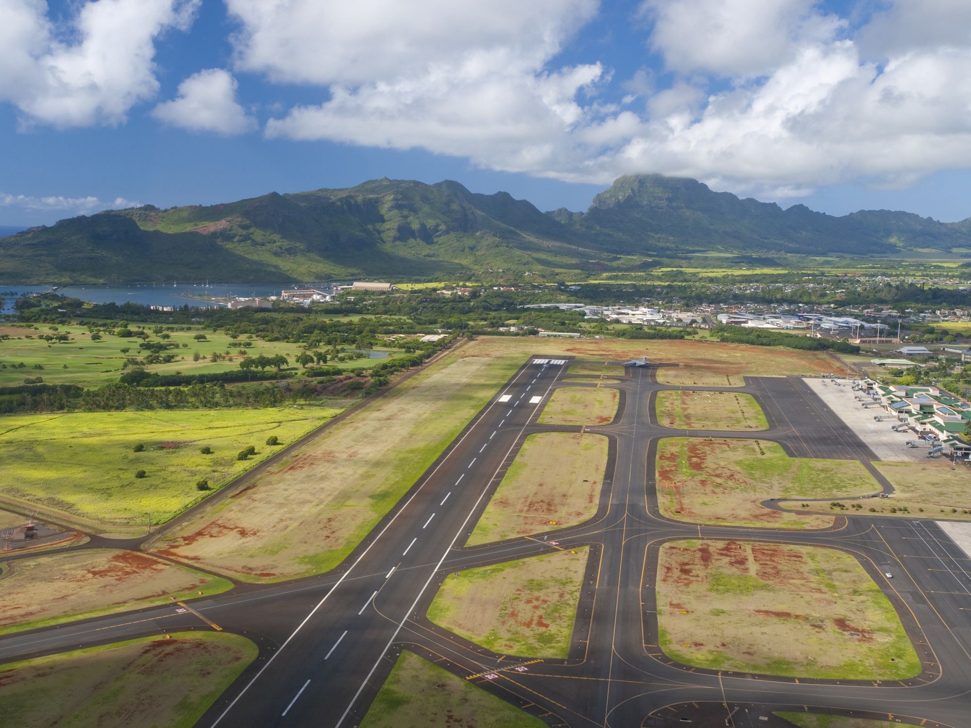 an aerial view of a runway with a city and mountains in the background