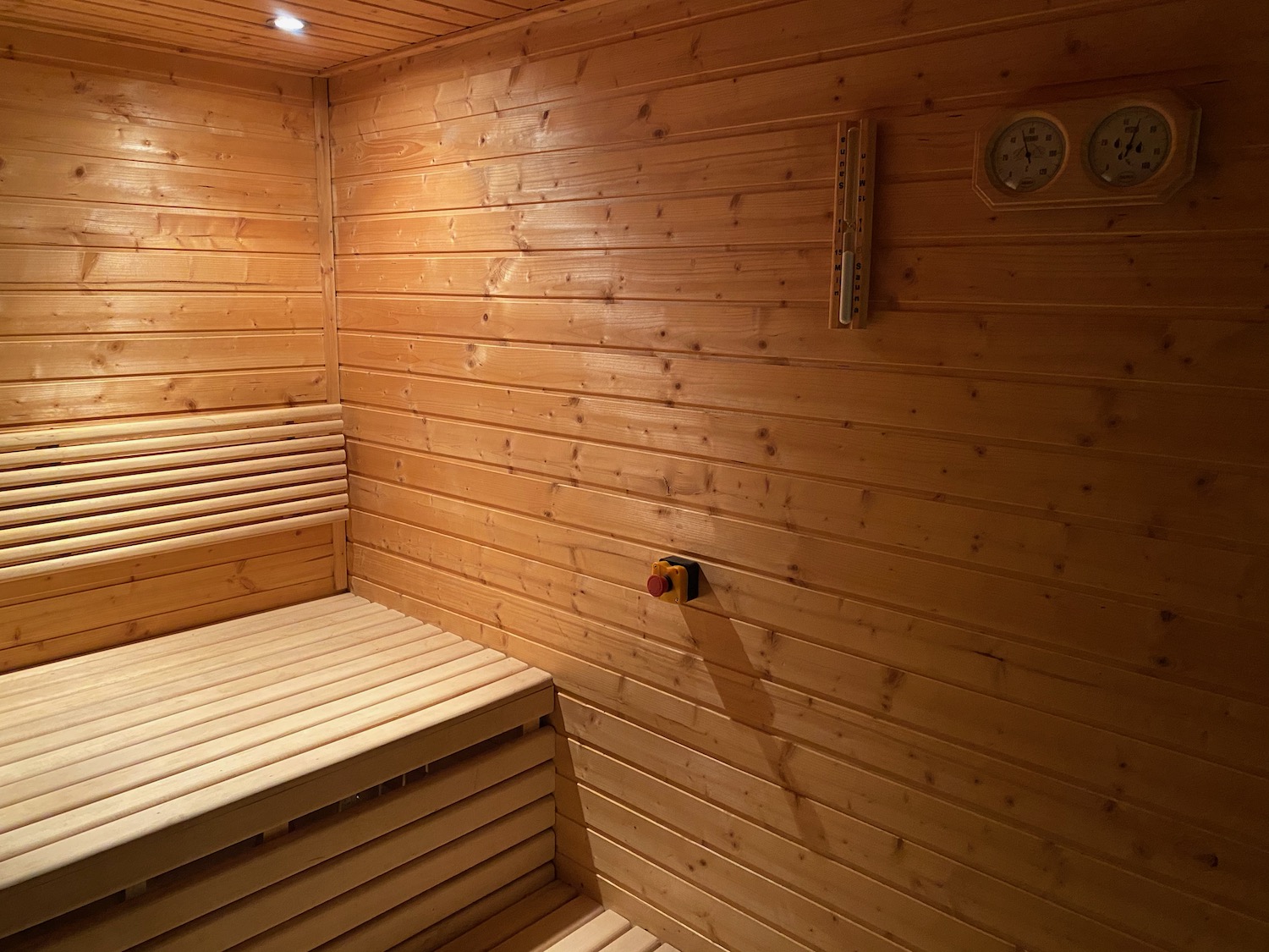 a wooden sauna with a red button and a clock
