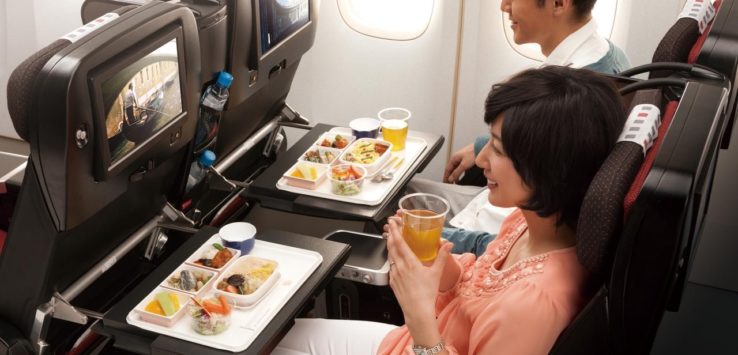 a couple of people sitting in an airplane eating food