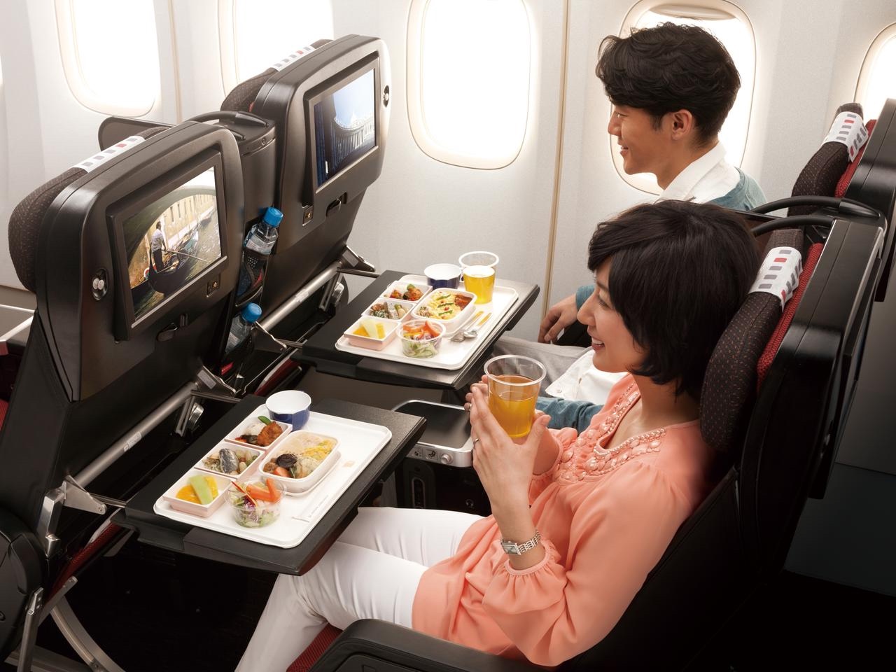 a couple of people sitting in an airplane eating food