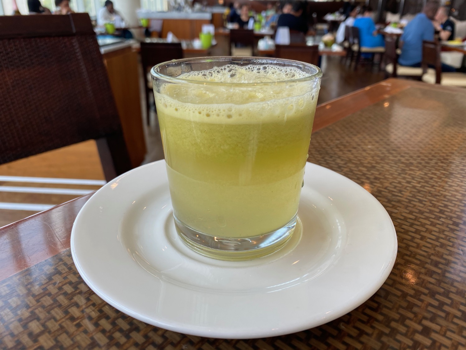 a glass of yellow liquid on a white plate