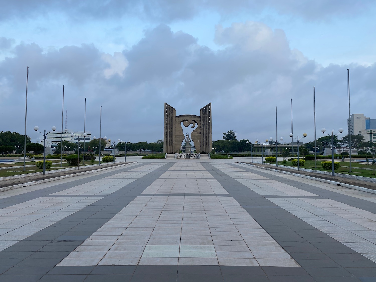 a stone archway with a statue in the middle of a paved area