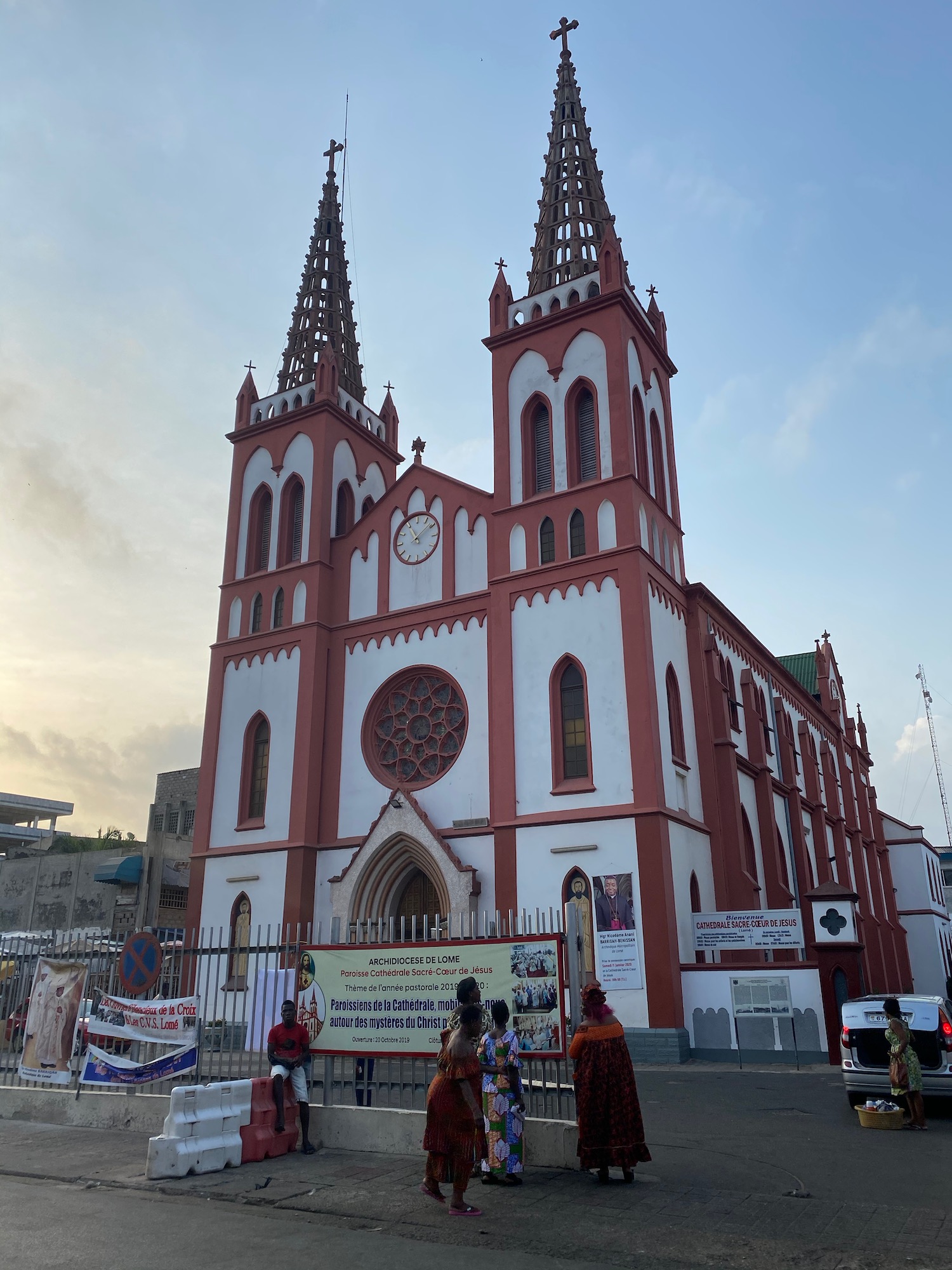 a church with a clock and people walking in front of it