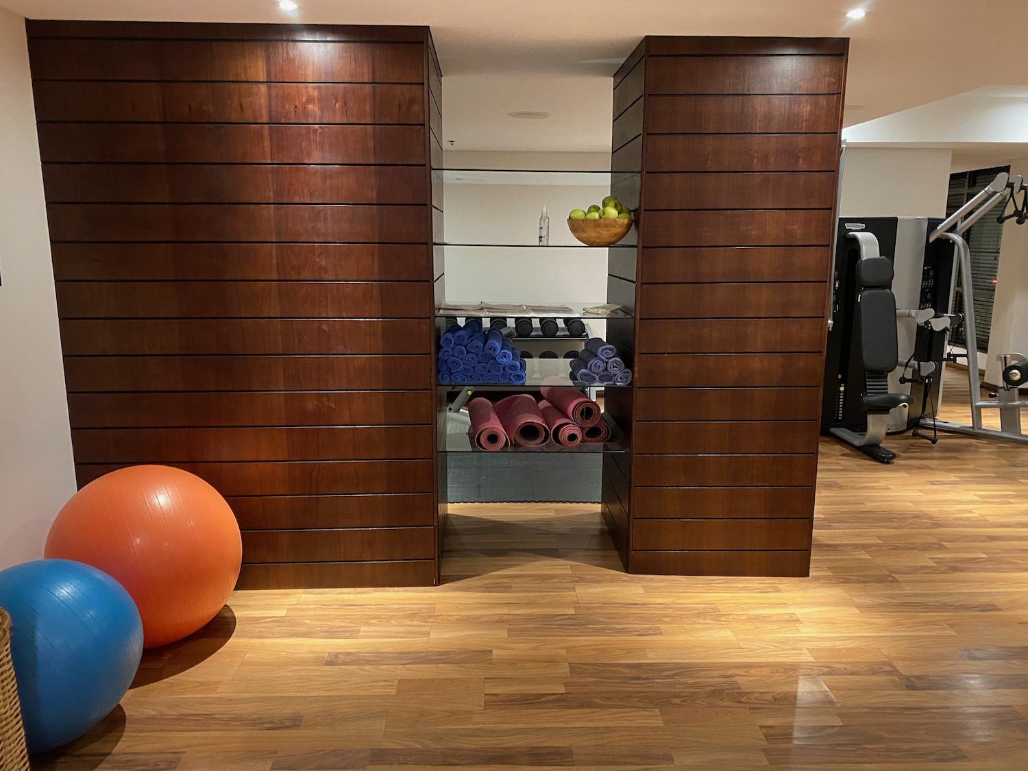 a room with a wood wall and shelves with yoga mats and exercise balls