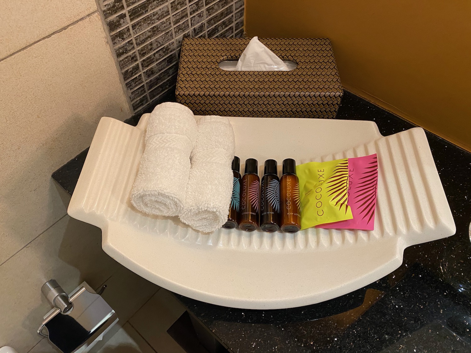 a white tray with bottles of toiletries and towels on it