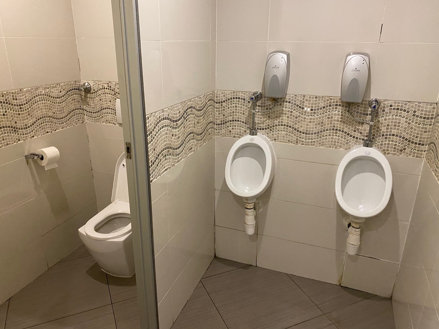 a bathroom with urinals and a glass door