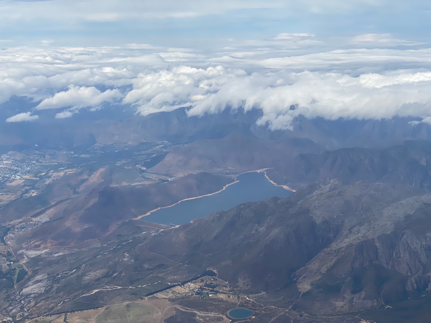 aerial view of a valley with a lake and clouds