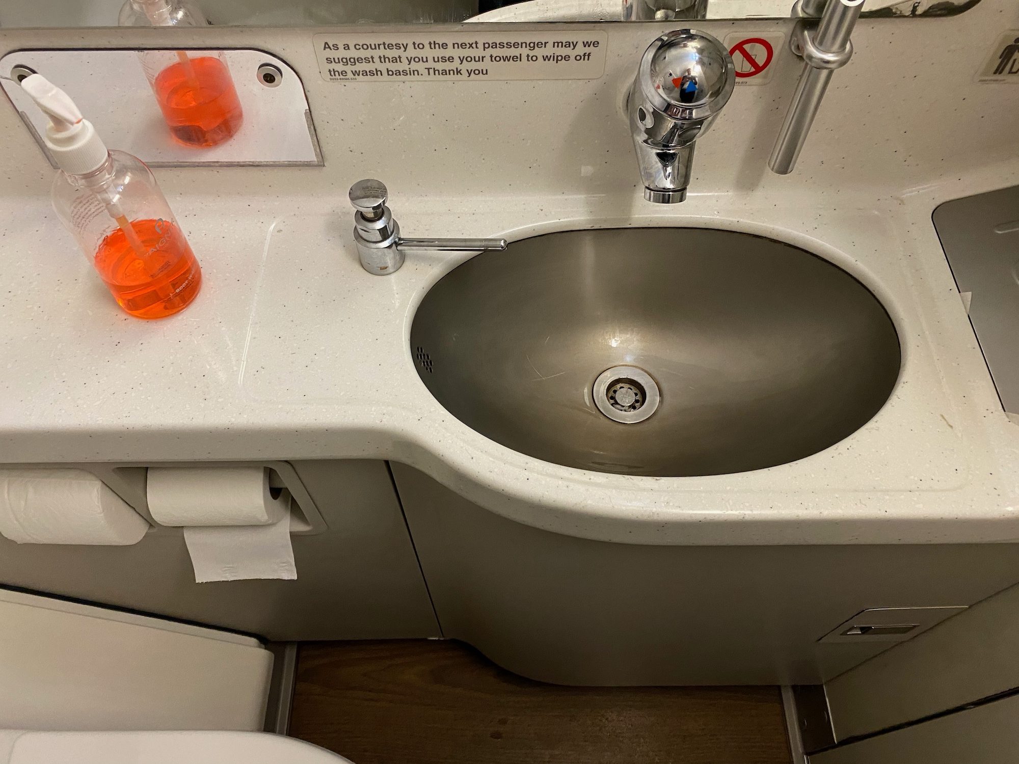 a sink with a toilet and a bottle of liquid