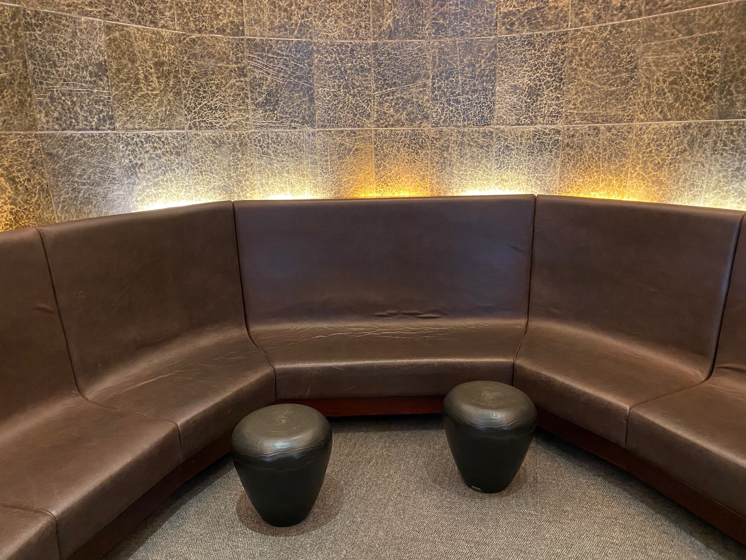 a brown couch with two stools in a room