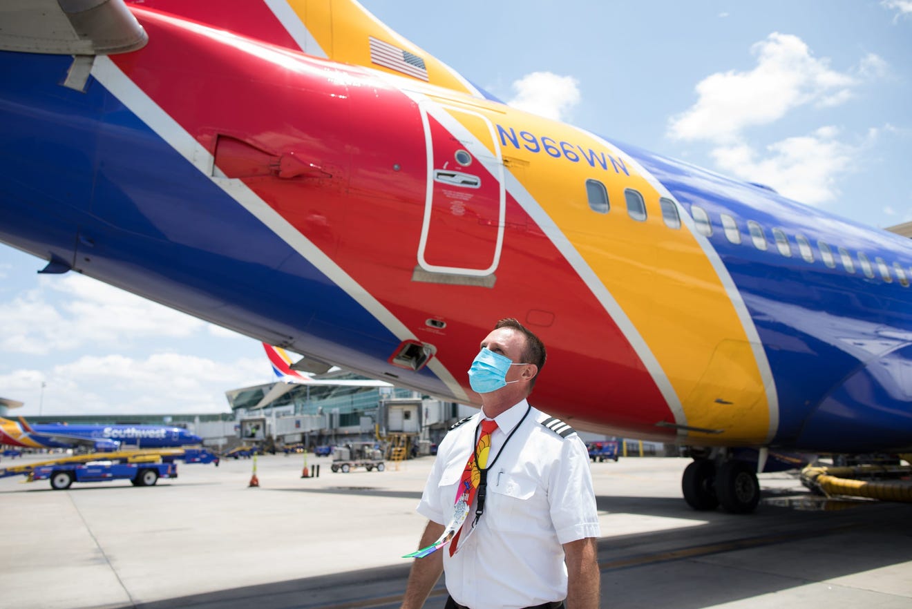 a man wearing a face mask standing next to a plane