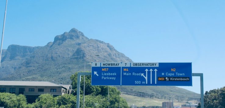 a road with a sign and a mountain in the background