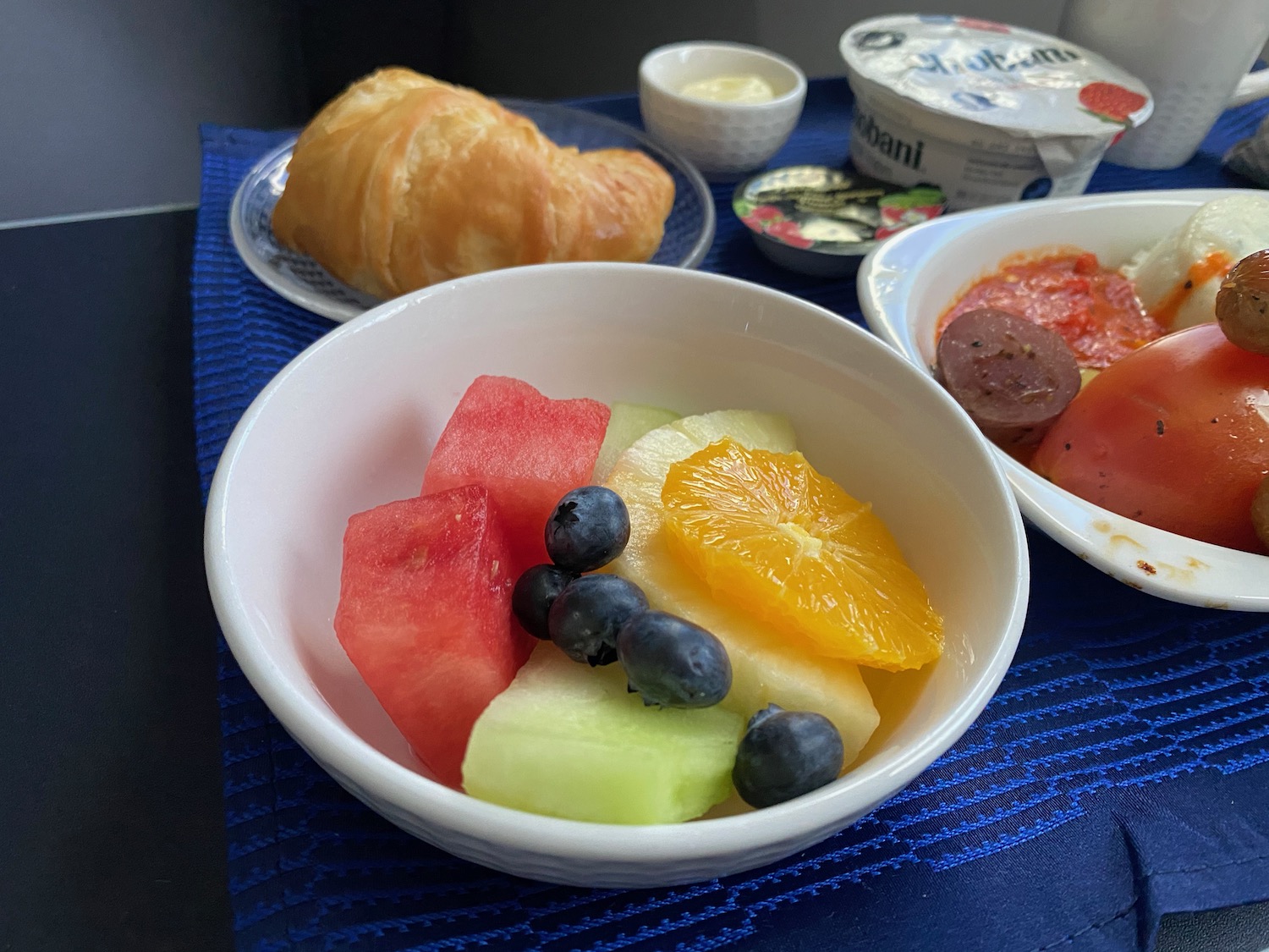a bowl of fruit and a croissant