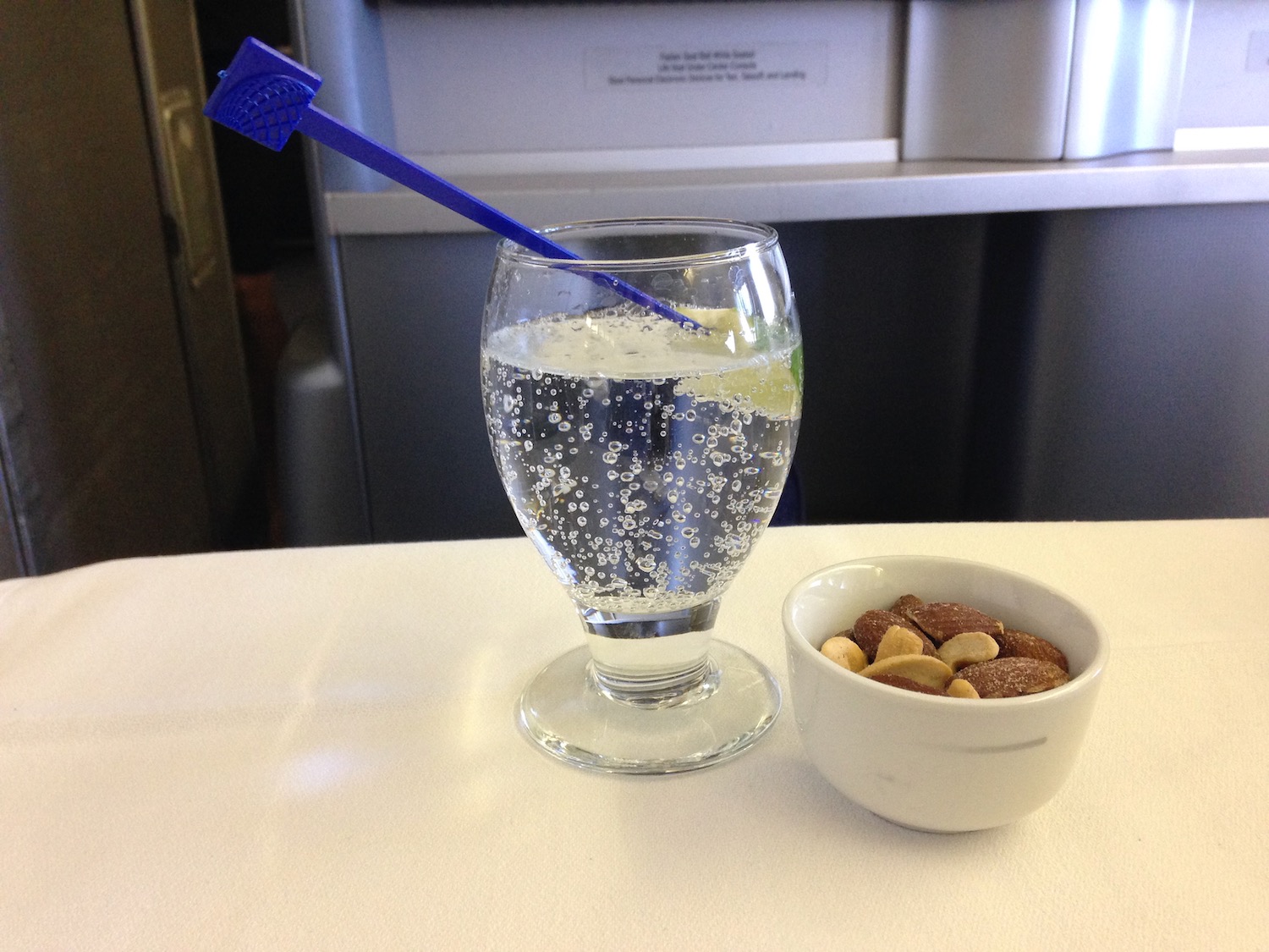 a glass of water with a blue straw in it and a bowl of nuts