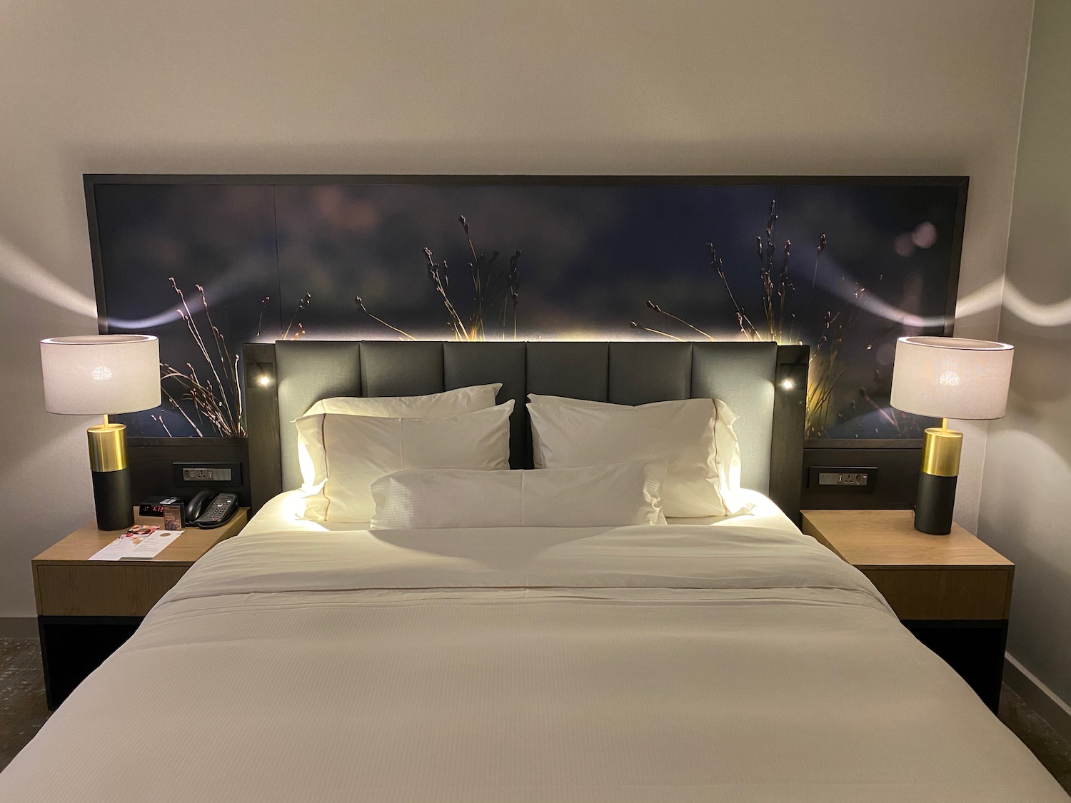 a bed with white sheets and lamps