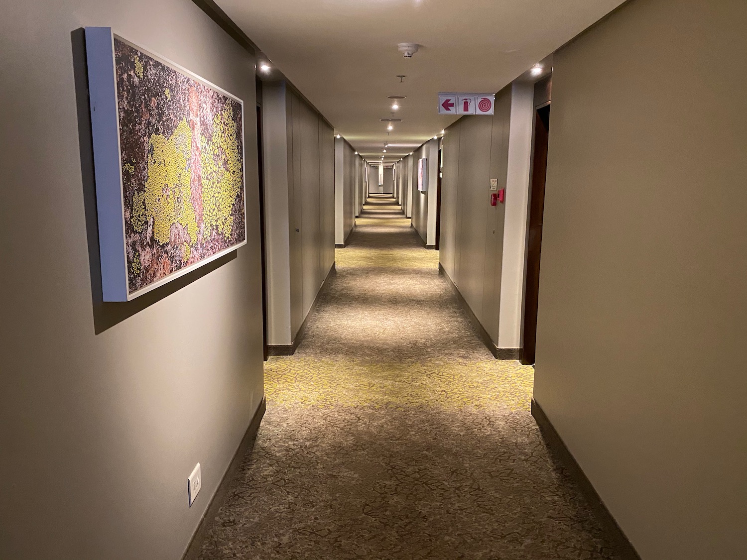 a long hallway with lights and a painting on the wall