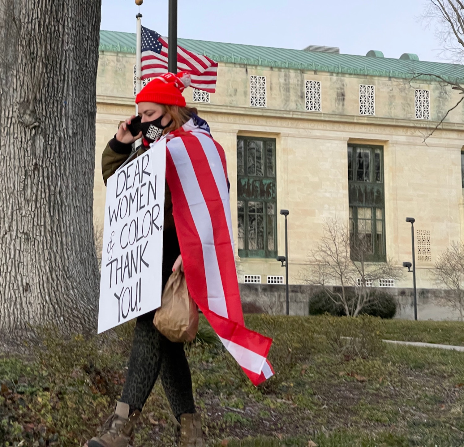 a woman wearing a red hat and a white sign with a flag