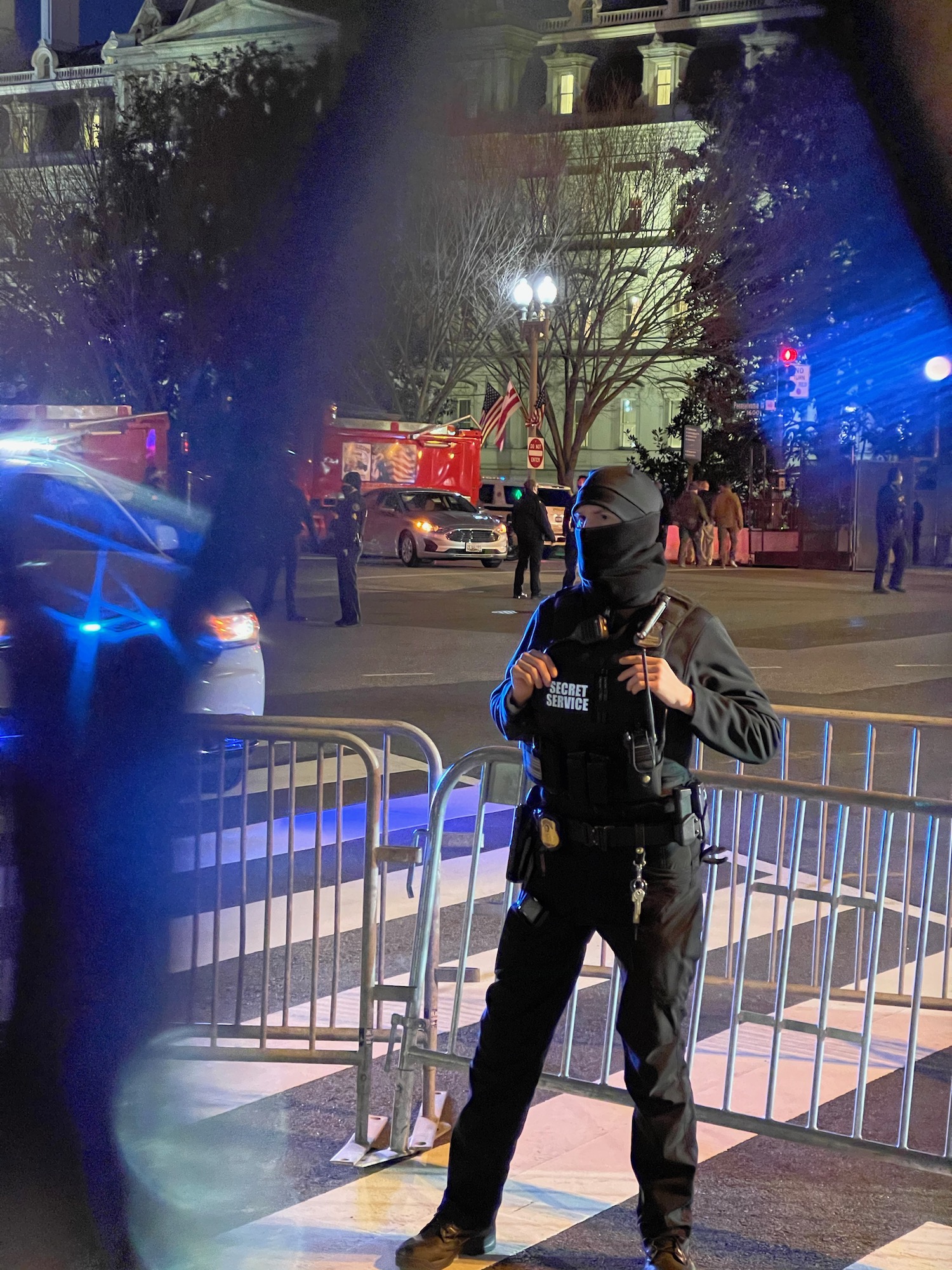 a man in a black mask standing in front of a metal fence