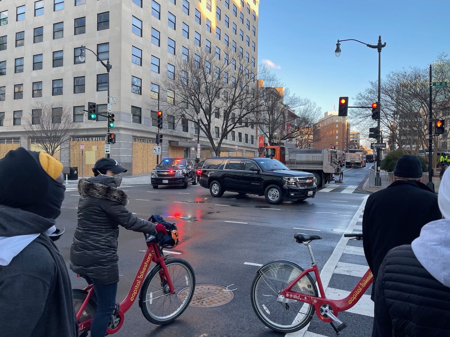 a group of people standing on a street with cars and bikes