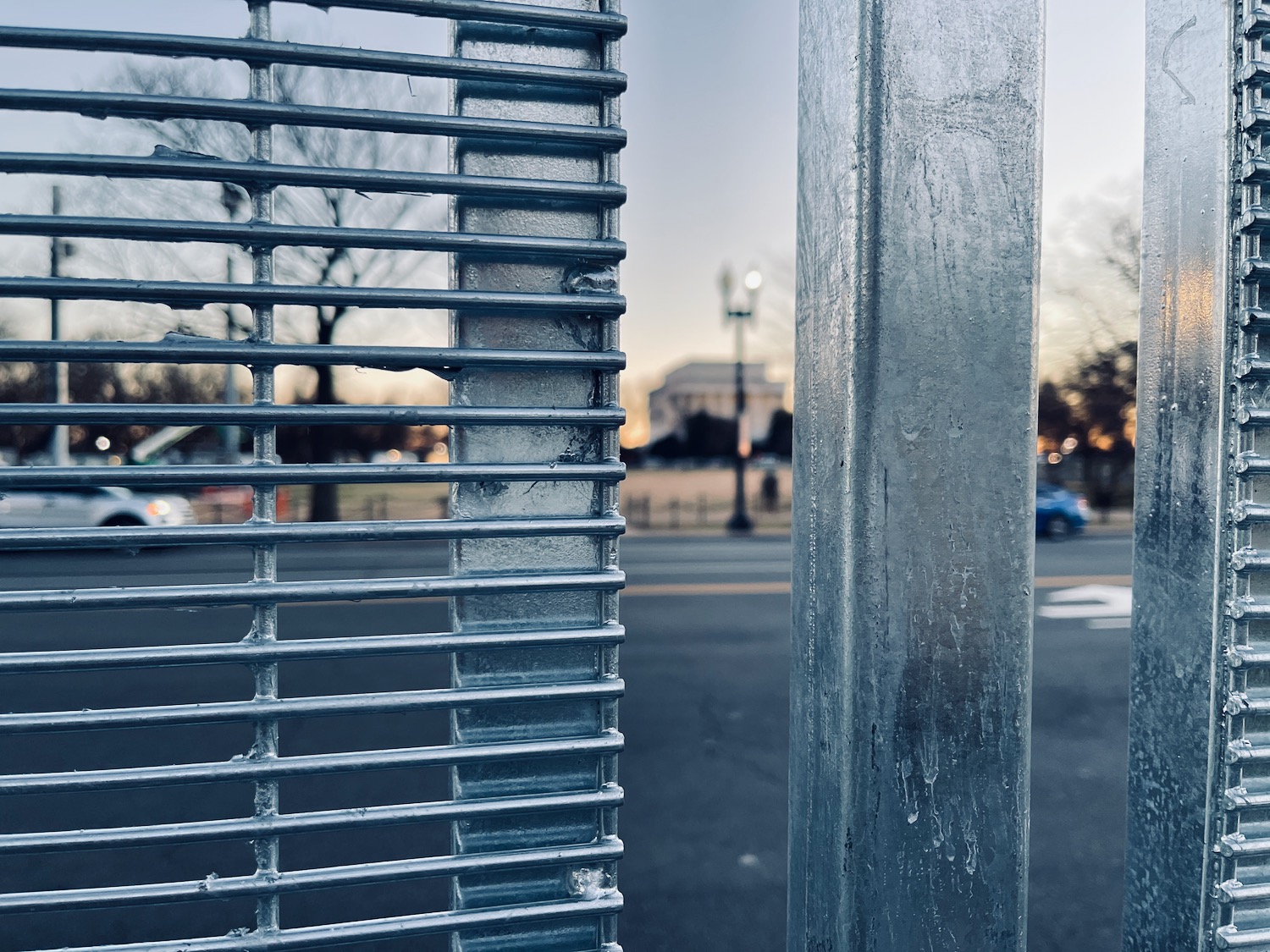 a metal fence with a street in the background