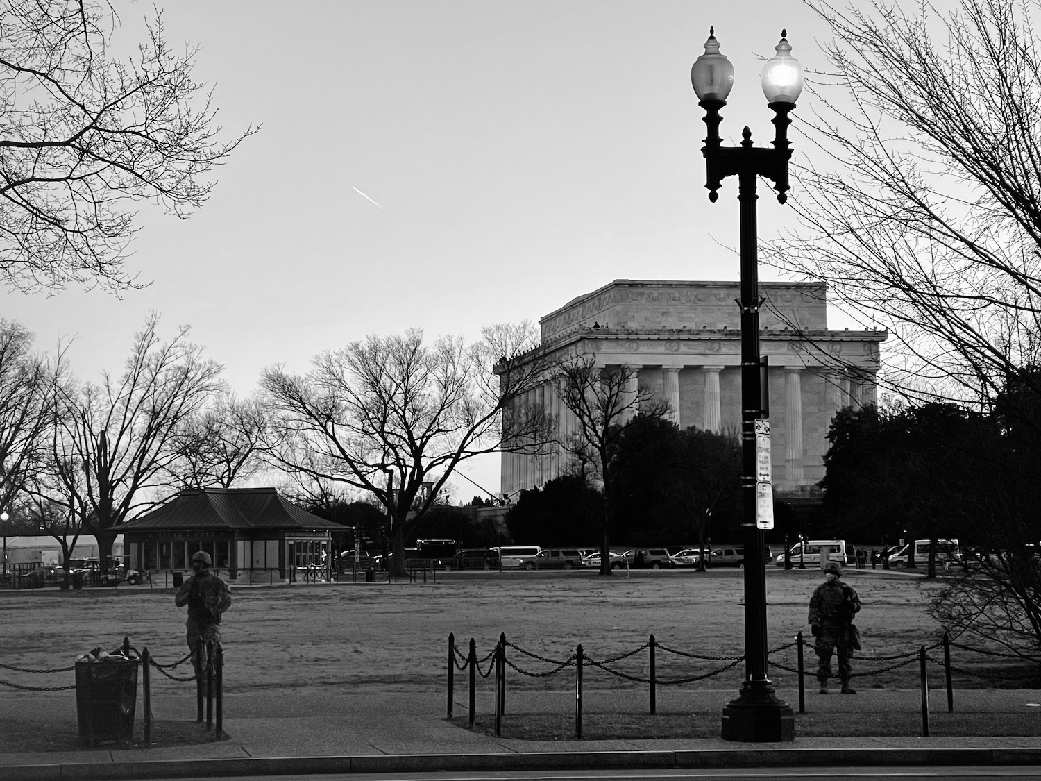 a black and white photo of a park with a building in the background