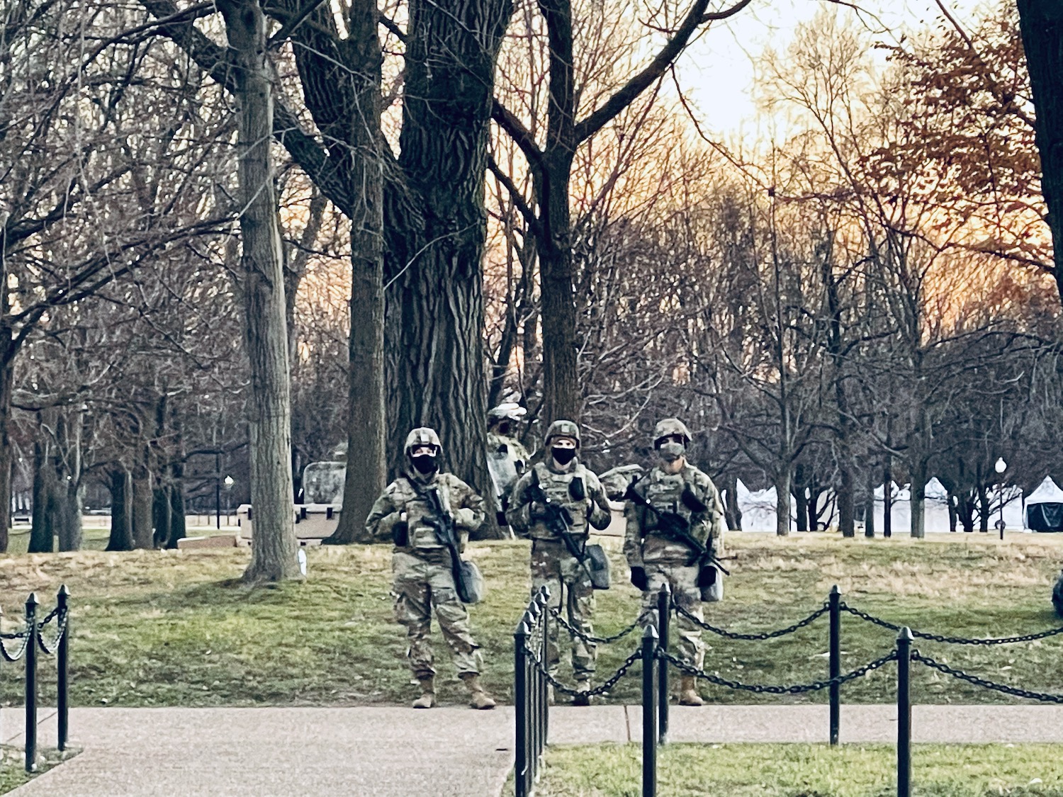 a group of people in camouflage standing in front of a fence