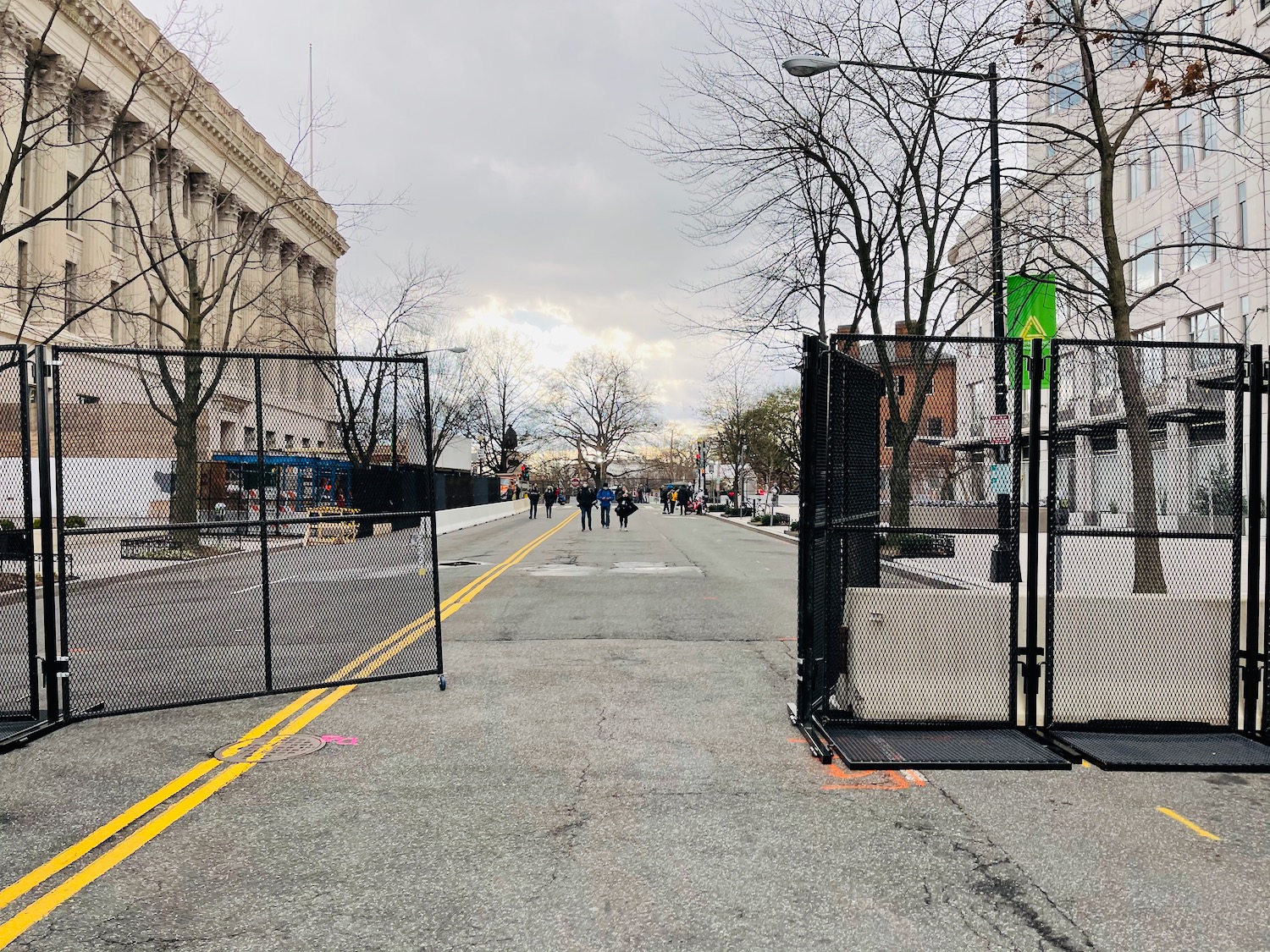 a street with a gate and people walking on it