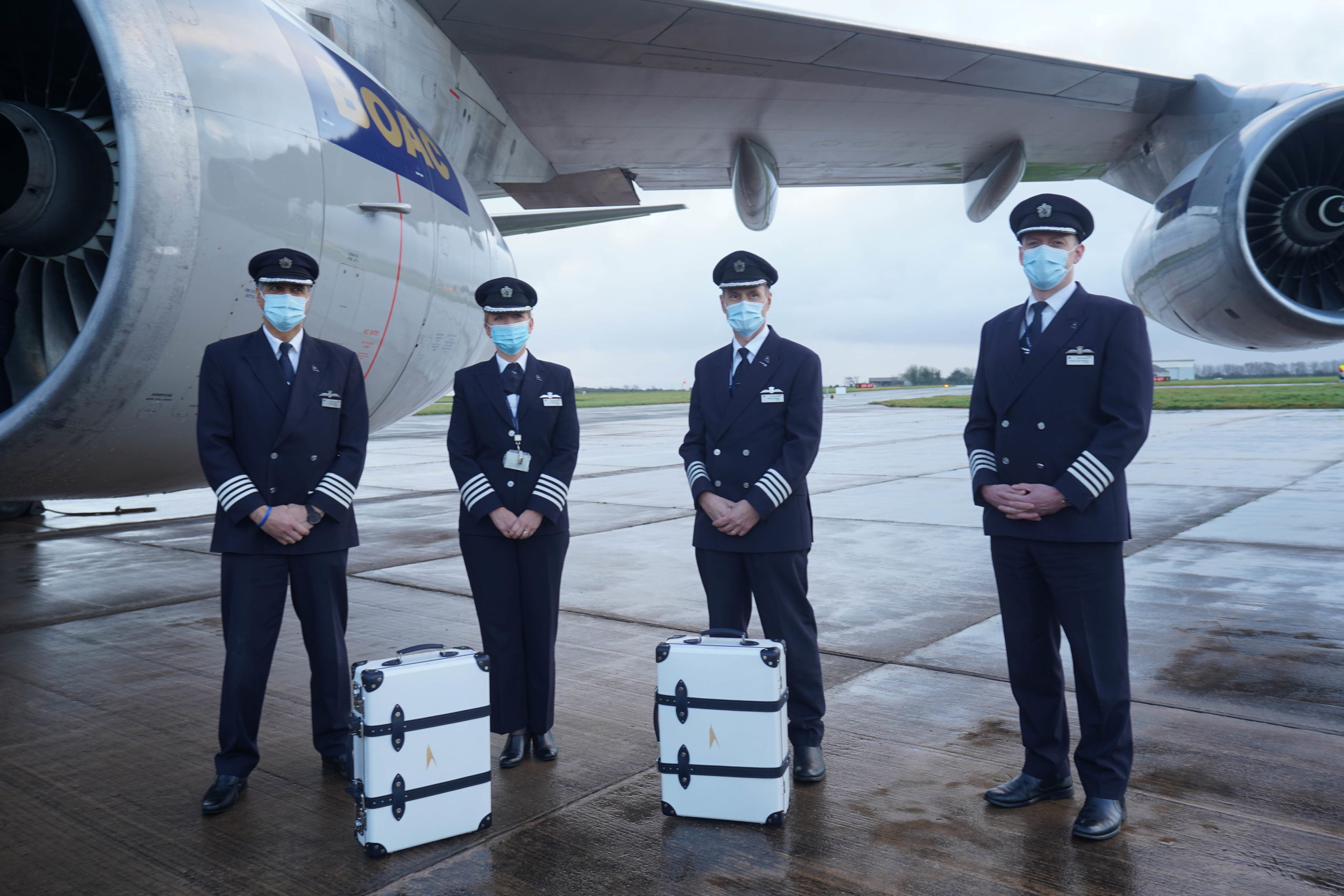 a group of people wearing face masks and standing in front of an airplane