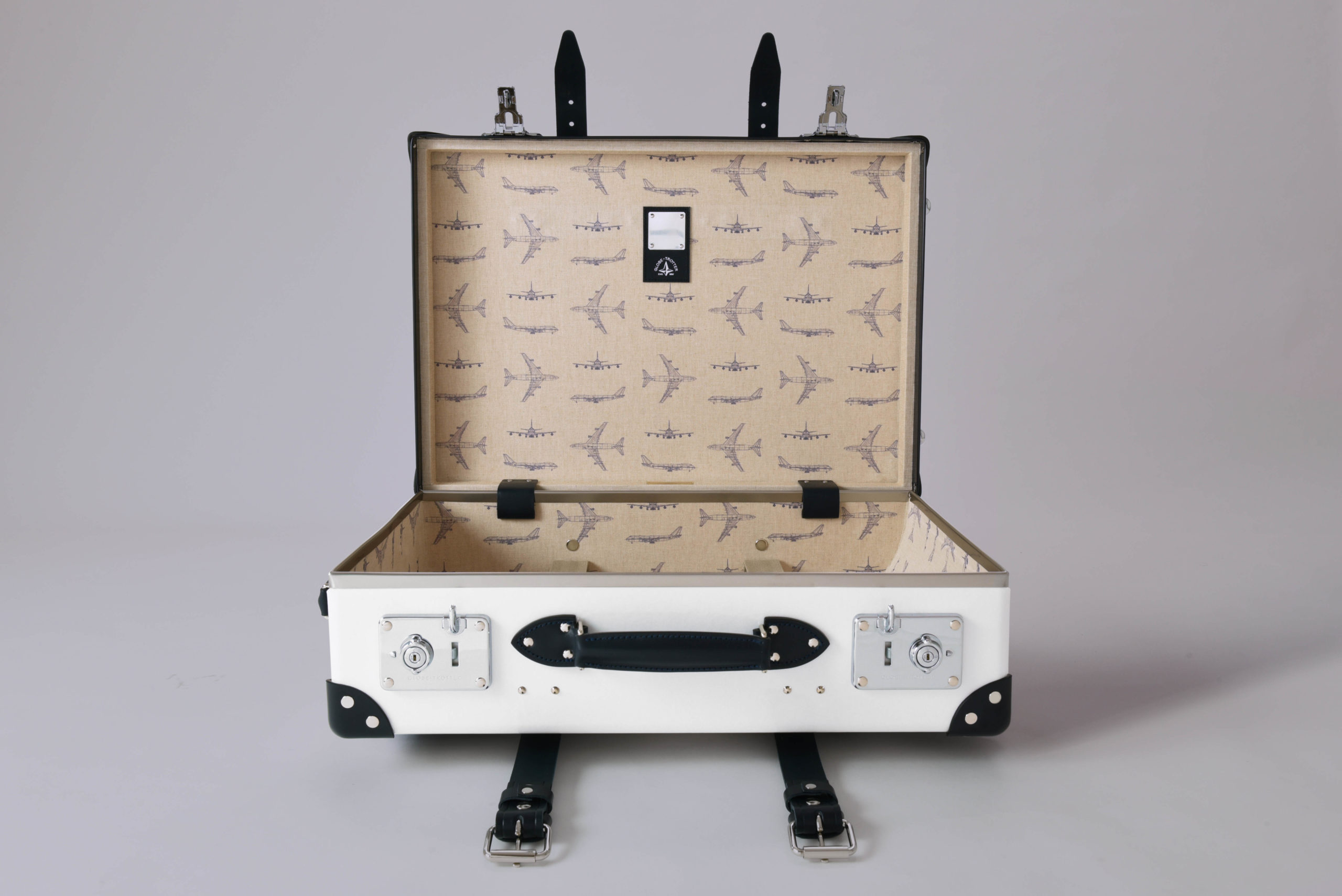 a white suitcase with black handles and a black handle